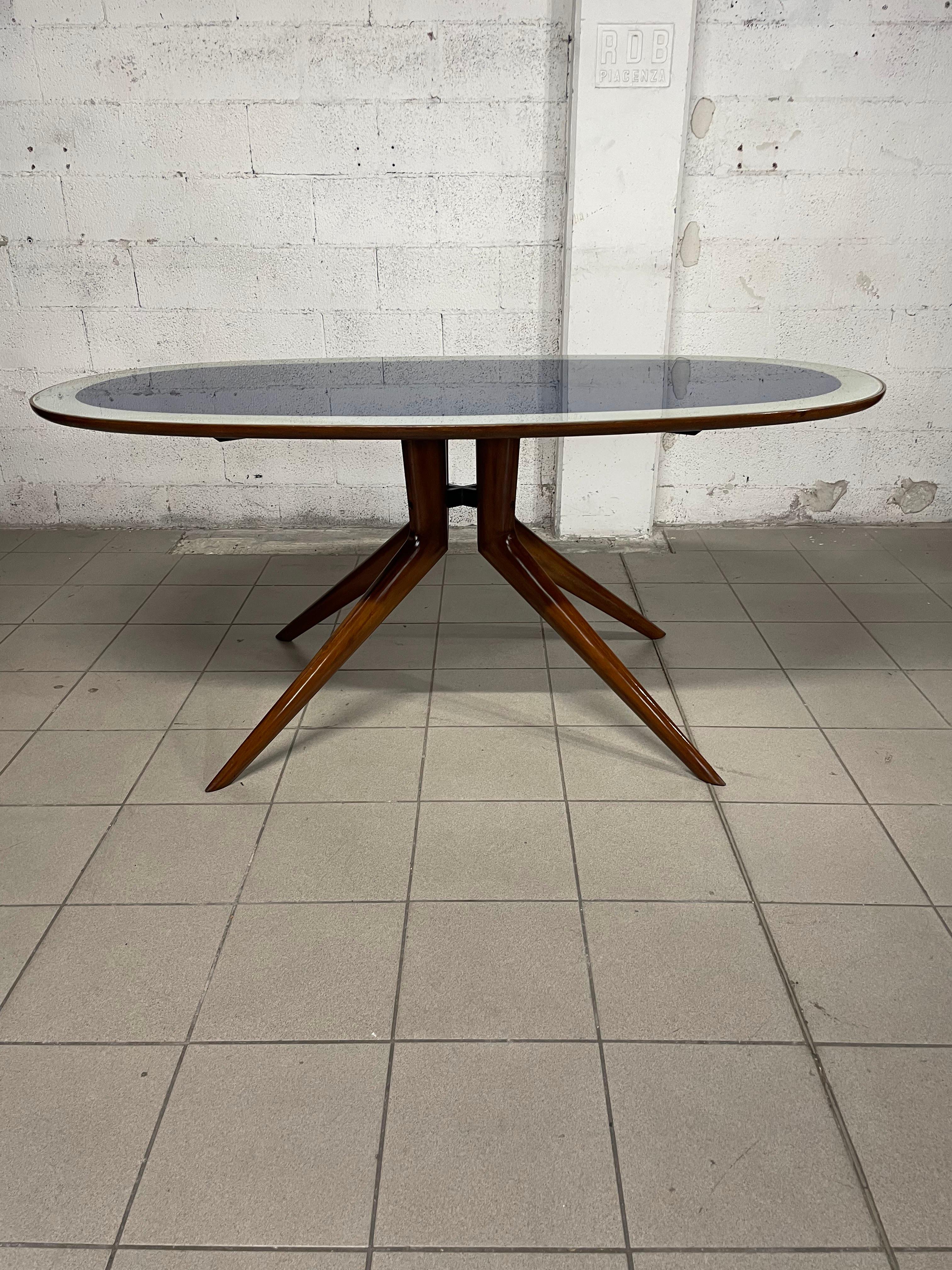 Table ovale des années 1950 avec structure en bois de hêtre poli et plateau en verre bicolore.

Elégant et adapté à tous les environnements.

Nous attirons l'attention sur le fait que le papier coloré situé sous le verre a souffert de l'humidité au