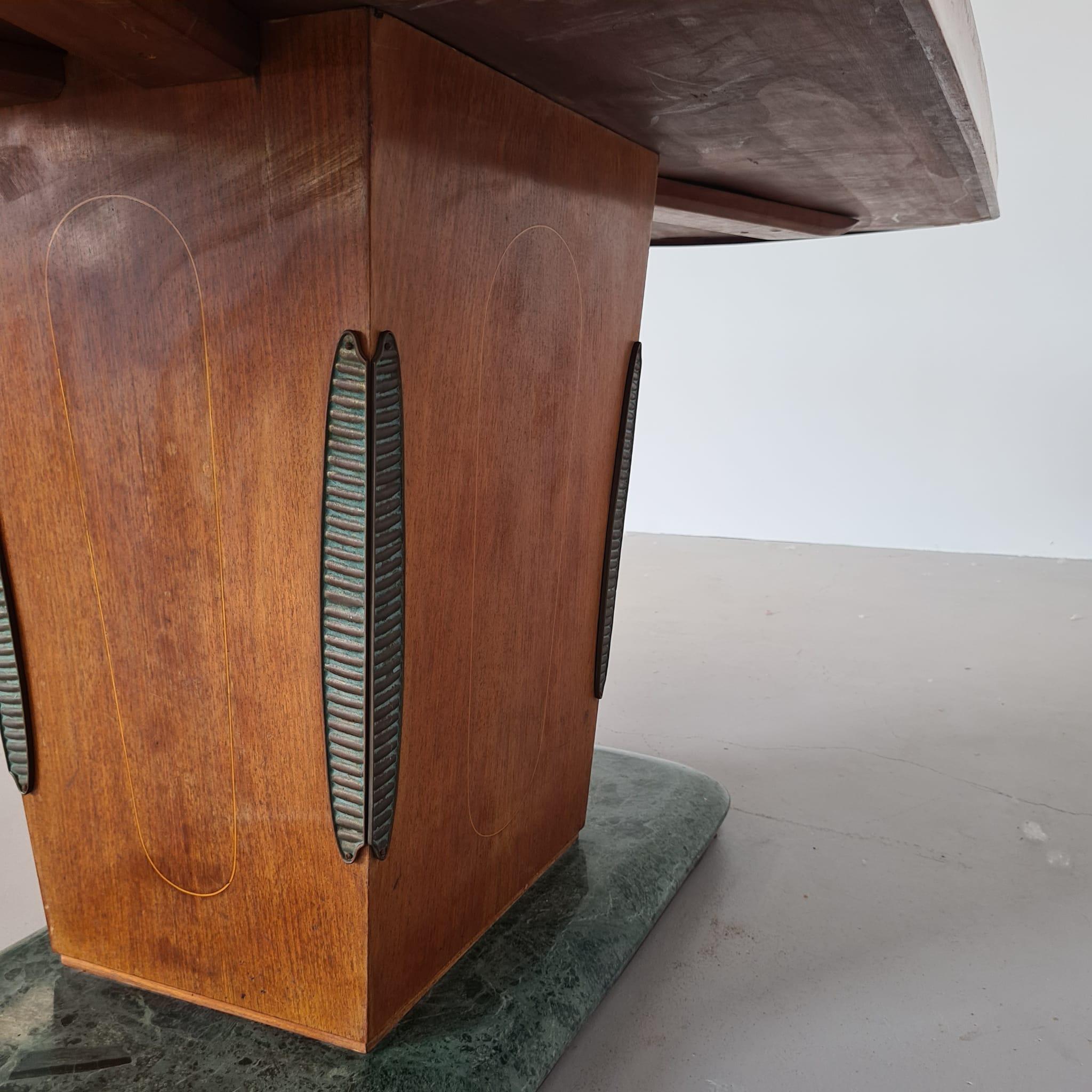 Elegante tavolo rettangolare anni 40/50 produzione Dassi / Cantù  e gamba centrale in legno con angolari in ottone. Piano in radica con vetro verde a incasso. Il Tavolo si presenta in Ottime condizioni generali con segni d'uso compatibili con l'età