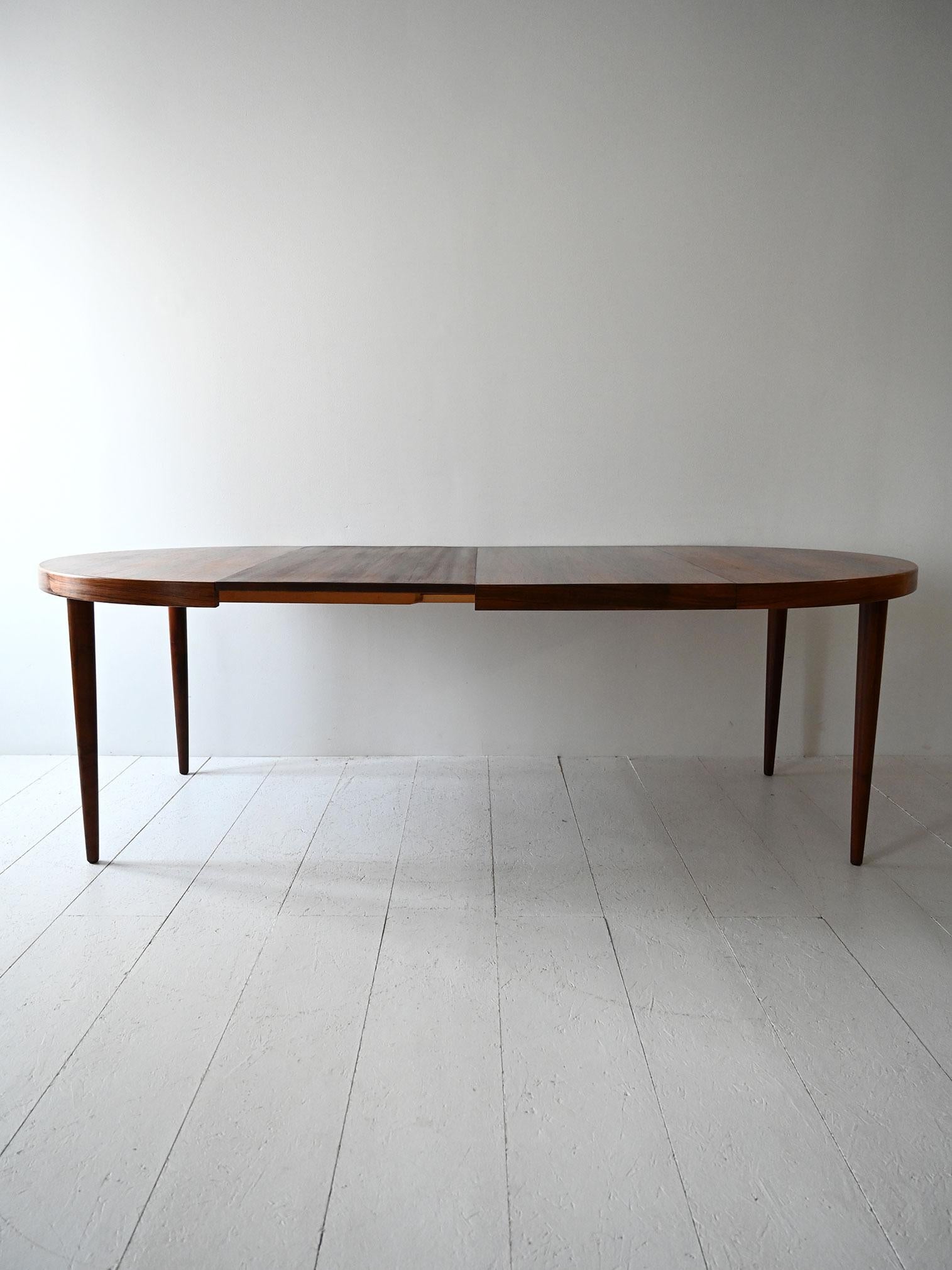 Tavolo rotondo allungabile in palissandro, con due allunghe centrali.

Tavolo da pranzo scandinavo vintage degli anni 1950/60 in palissandro, con piano rotondo e due ante centrali. Le gambe affusolate e le linee pulite esaltano le ricche venature