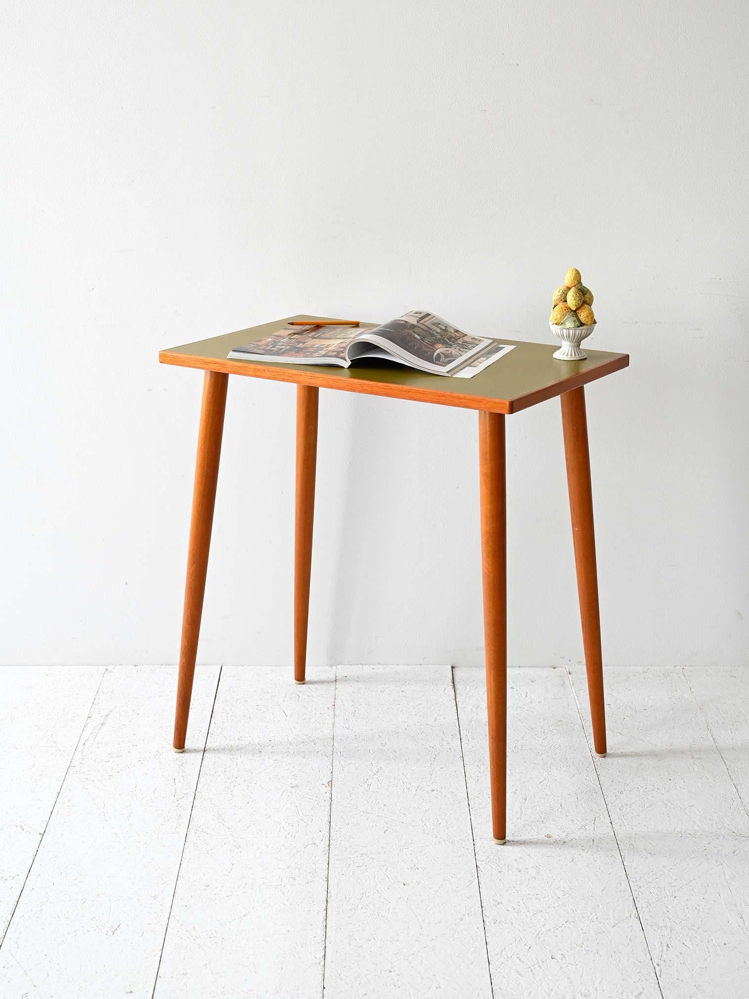 Estructura ligera de teca con tablero de fórmica verde oliva y patas cónicas torneadas.

Mesa escandinava vintage de los años 50/60 con tablero rectangular de formica verde oliva. Las esbeltas patas cónicas son de teca torneada, sólidamente fijadas