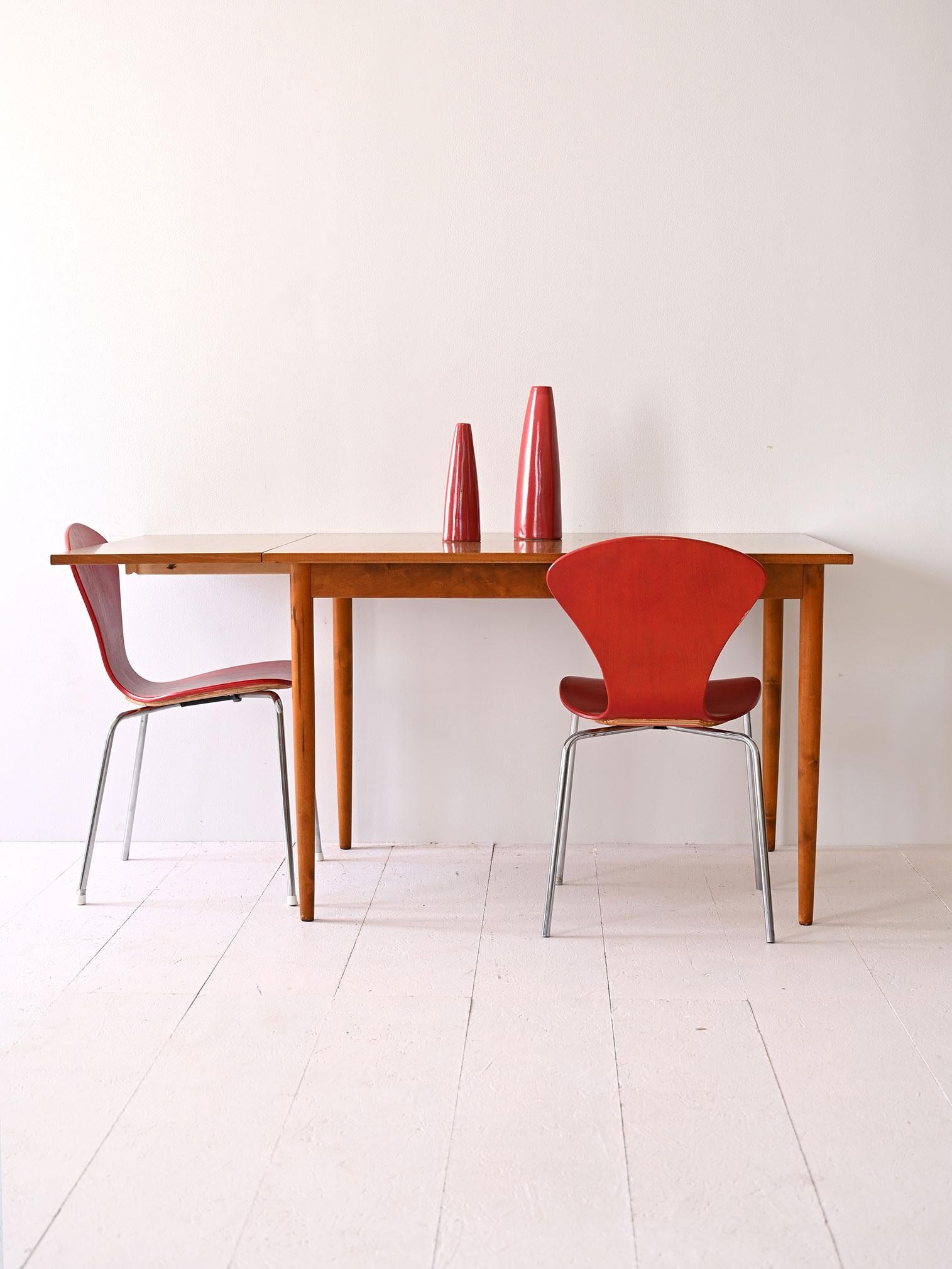 Mesa escandinava de los años 70, con tablero de formica y marco de madera. La mesa es extensible gracias a un tablón adicional. Longitud sin eje 110 cm, con eje 150 cm.

Mesa escandinava fabricada en los años 70, con tablero de formica y marco de