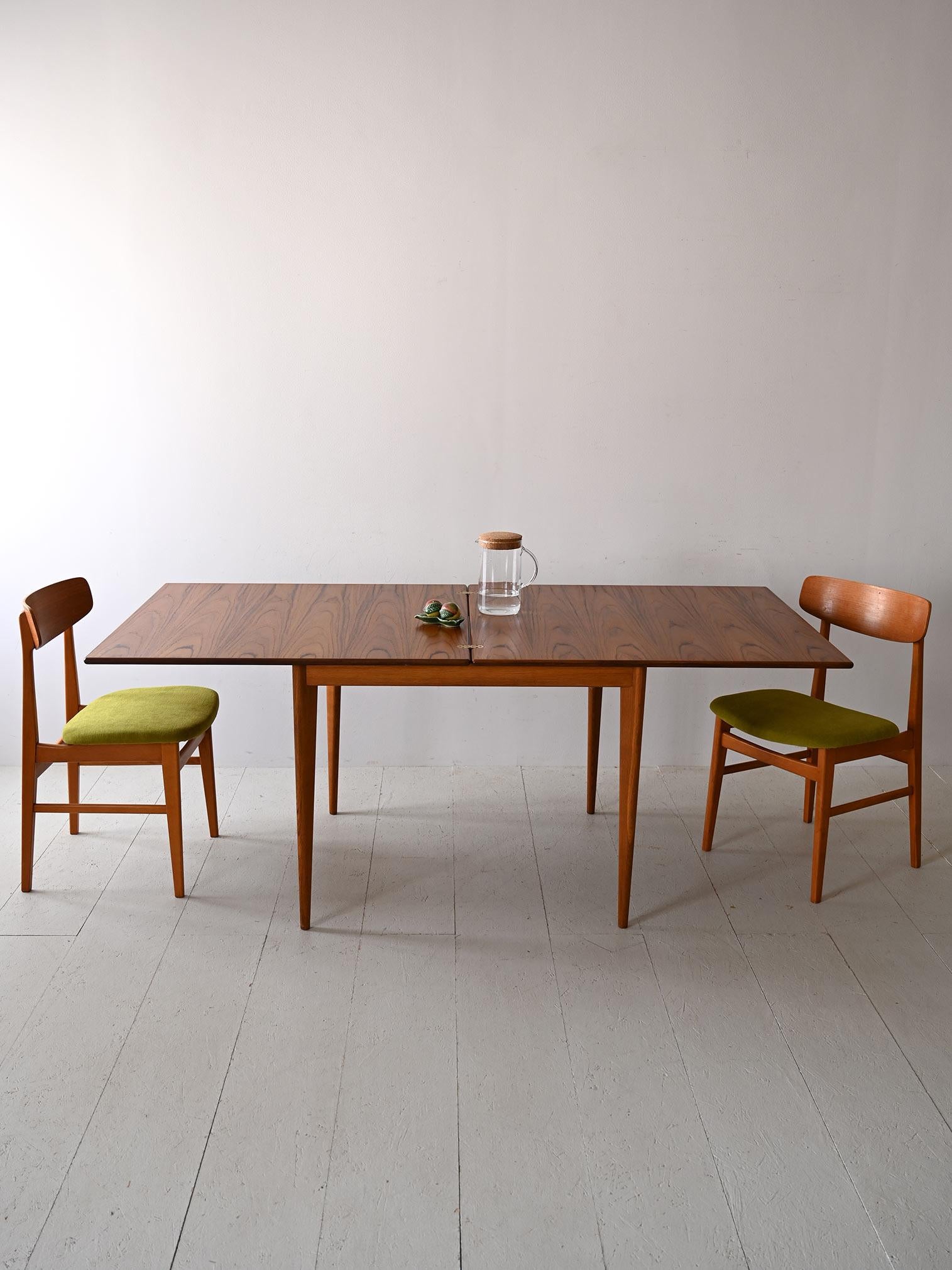 Questo tavolo estendibile in teak, tipico del design scandinavo degli anni '60, offre un equilibrio perfetto tra funzionalità e stile. Le gambe sottili e il bordo smussato del piano sottolineano la sua eleganza intrinseca, mentre la capacità di