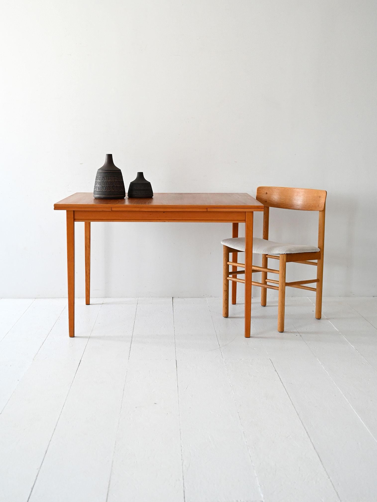 Tavolo scandinavo anni ’60 in teak, allungabile con due ali laterali. Design essenziale e funzionale tipico del mid-century nordico.

Tavolo scandinavo vintage dei primi anni ’60, realizzato in teak con bordo scanalato e due allunghe laterali ad