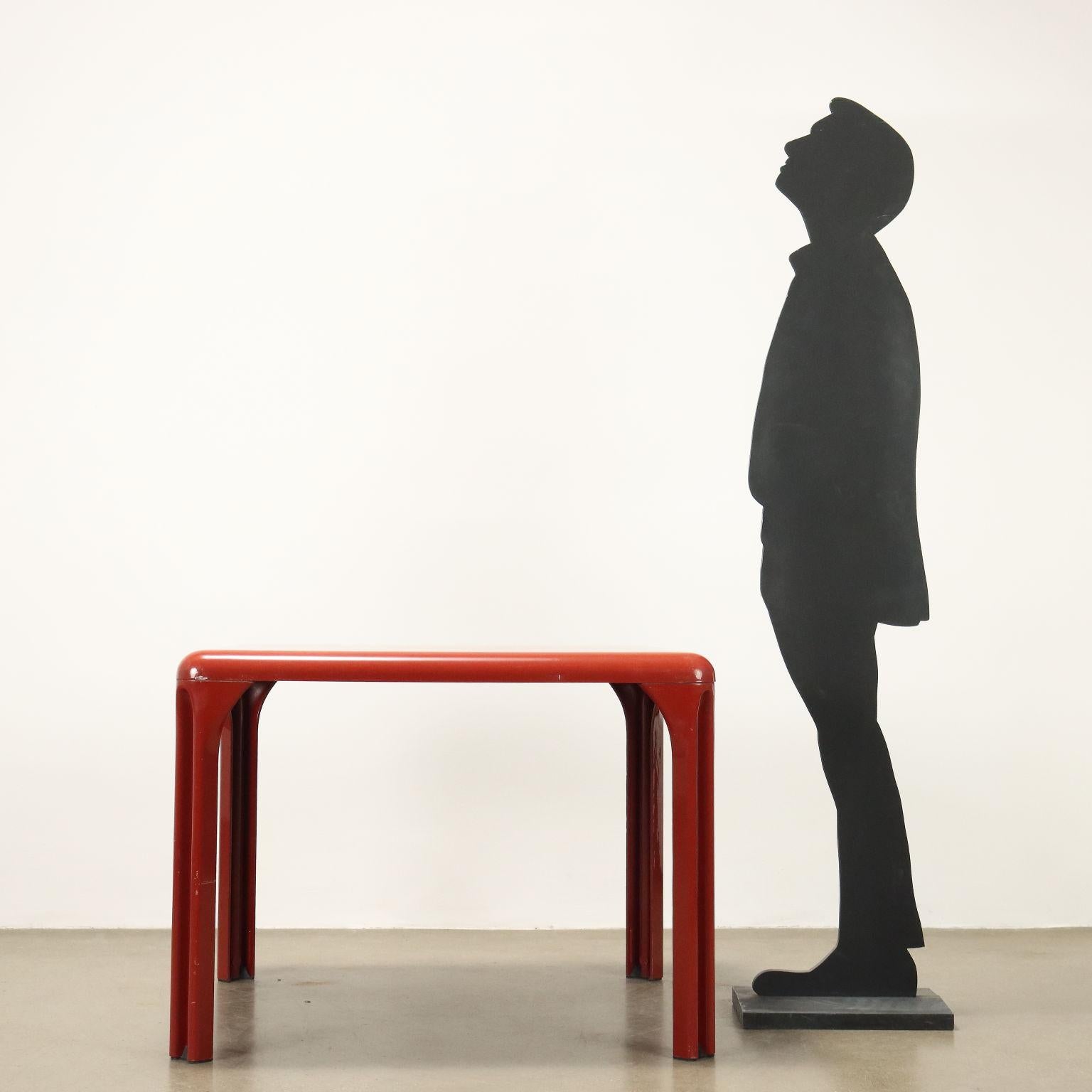 Tavolo da pranzo vintage in materiale plastico rosso con piano quadrato e angoli smussati.