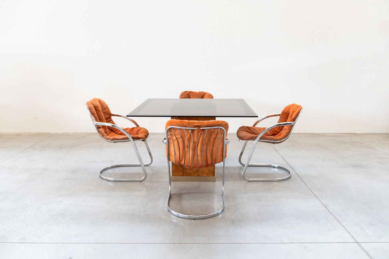 Willy Rizzo style table and chairs by Gastone Rinaldi for Rima, 1970s	
DESCRIPTION	Table with briarwood and brass base, and smoked glass top. The chairs are made of chrome-plated iron with suede upholstery
PIECES	5
DESIGN PERIOD	1970
PRODUCTION