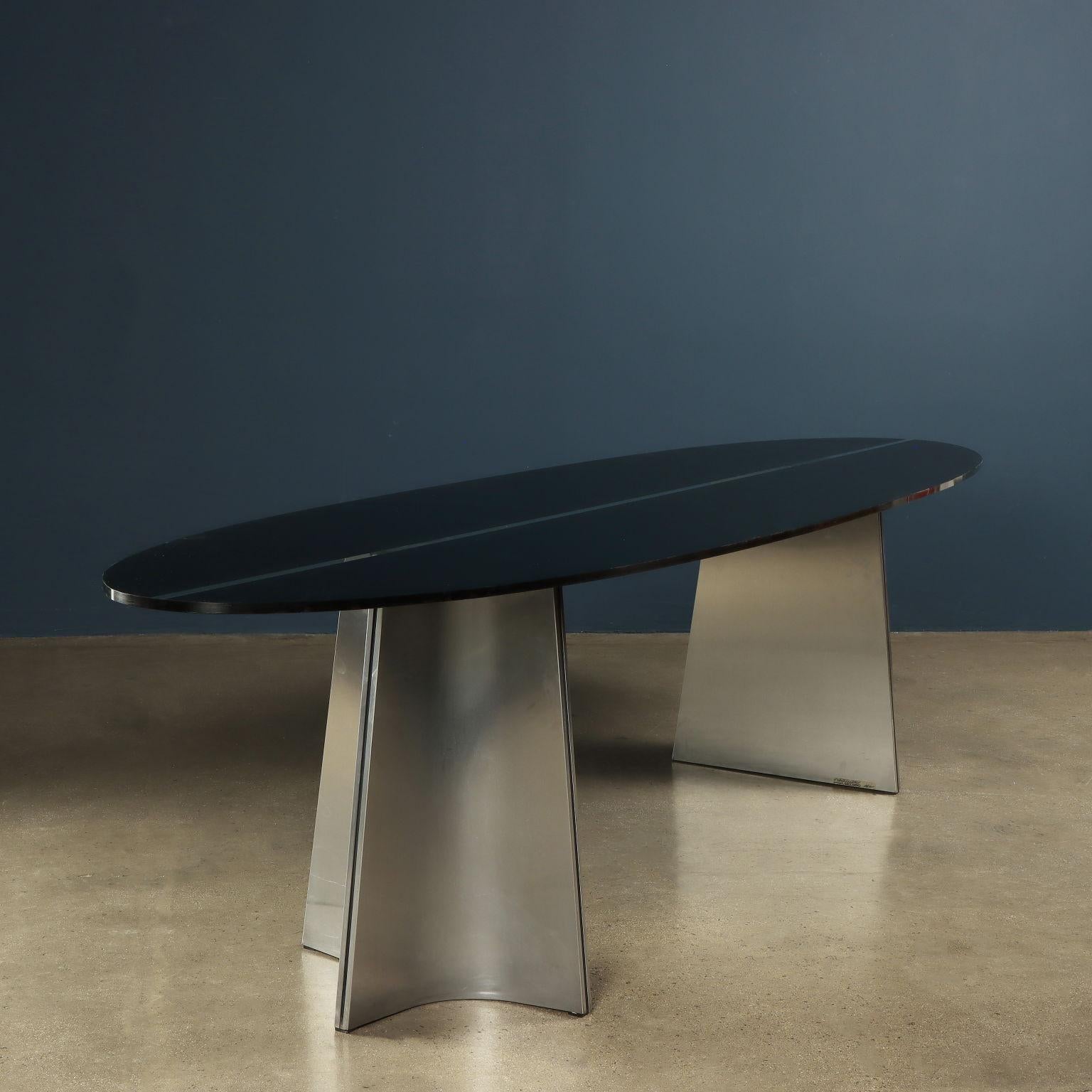 Mesa diseñada y fabricada en la década de 1970 con patas de acero cepillado y tablero de cristal esmerilado parcialmente pintado de negro en la parte posterior. Muy buen estado