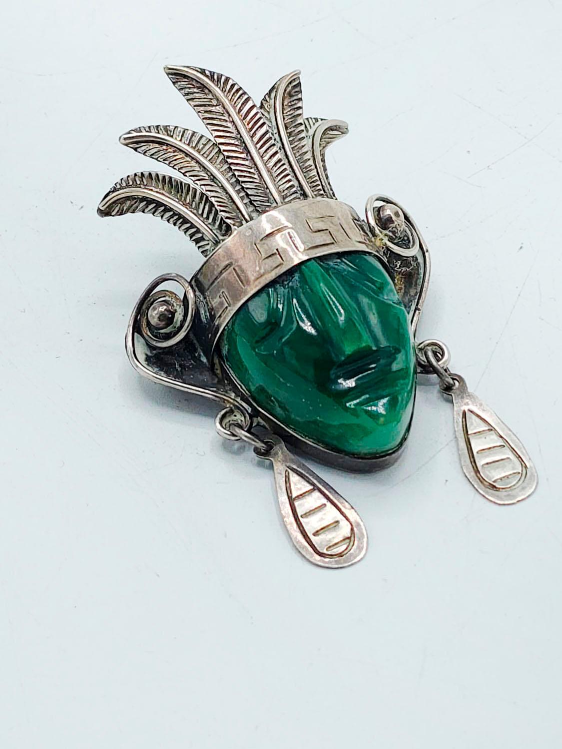 Taxco Sterling Mask Brooch with Large Green Agate and Stamped Details

925 silver brooch with carved details and green agate stone from an ancient Mexican mask is a beautiful piece that stands out on its own.
 Measures:
Heigth: 6 centimeters
Width: