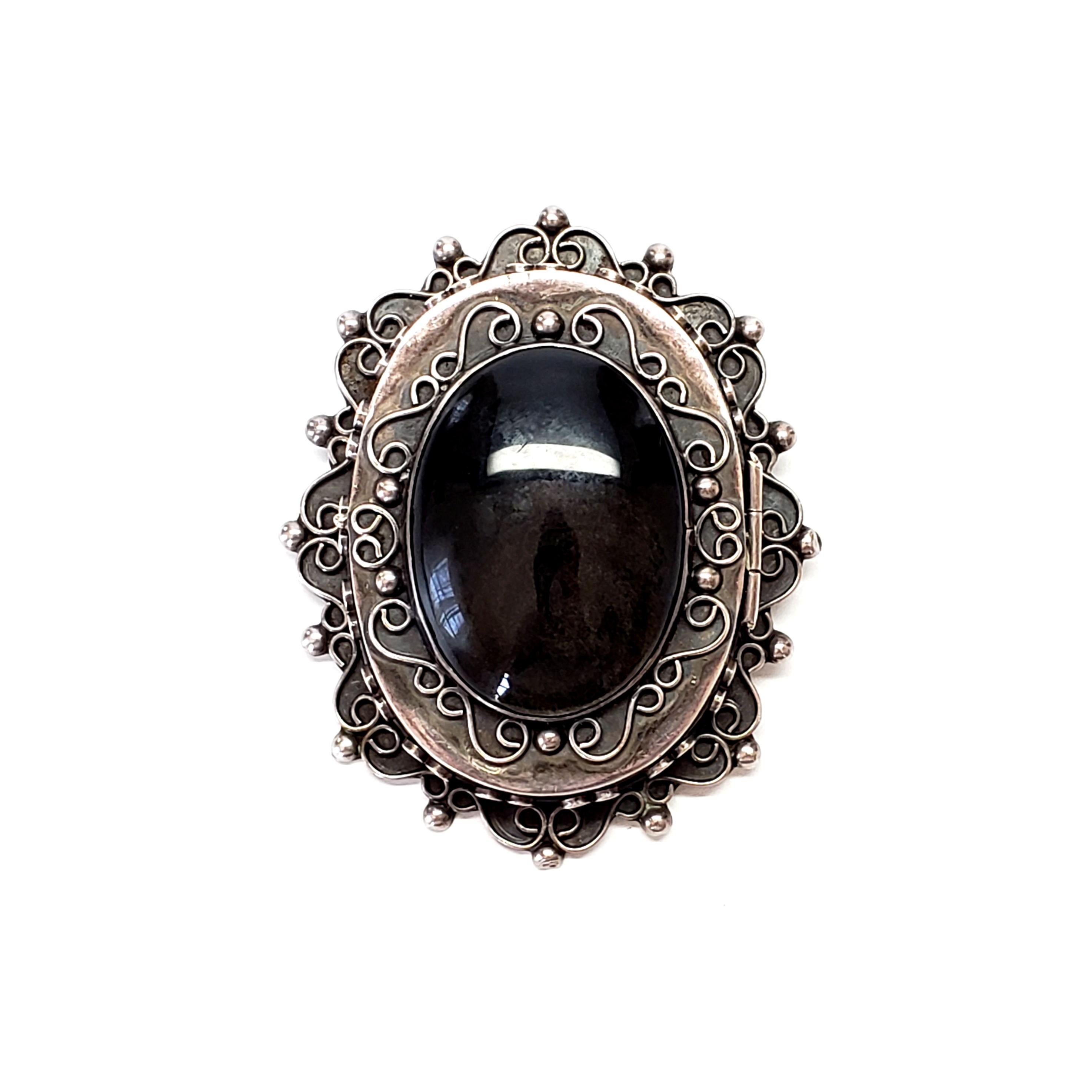 Taxco Mexico sterling silver and obsidian large locket by artisan Aartenca.

Large and ornate oval locket that can be worn as a pendant or a pin. Stone has beautiful depth of color.

Measures approx 2 3/4