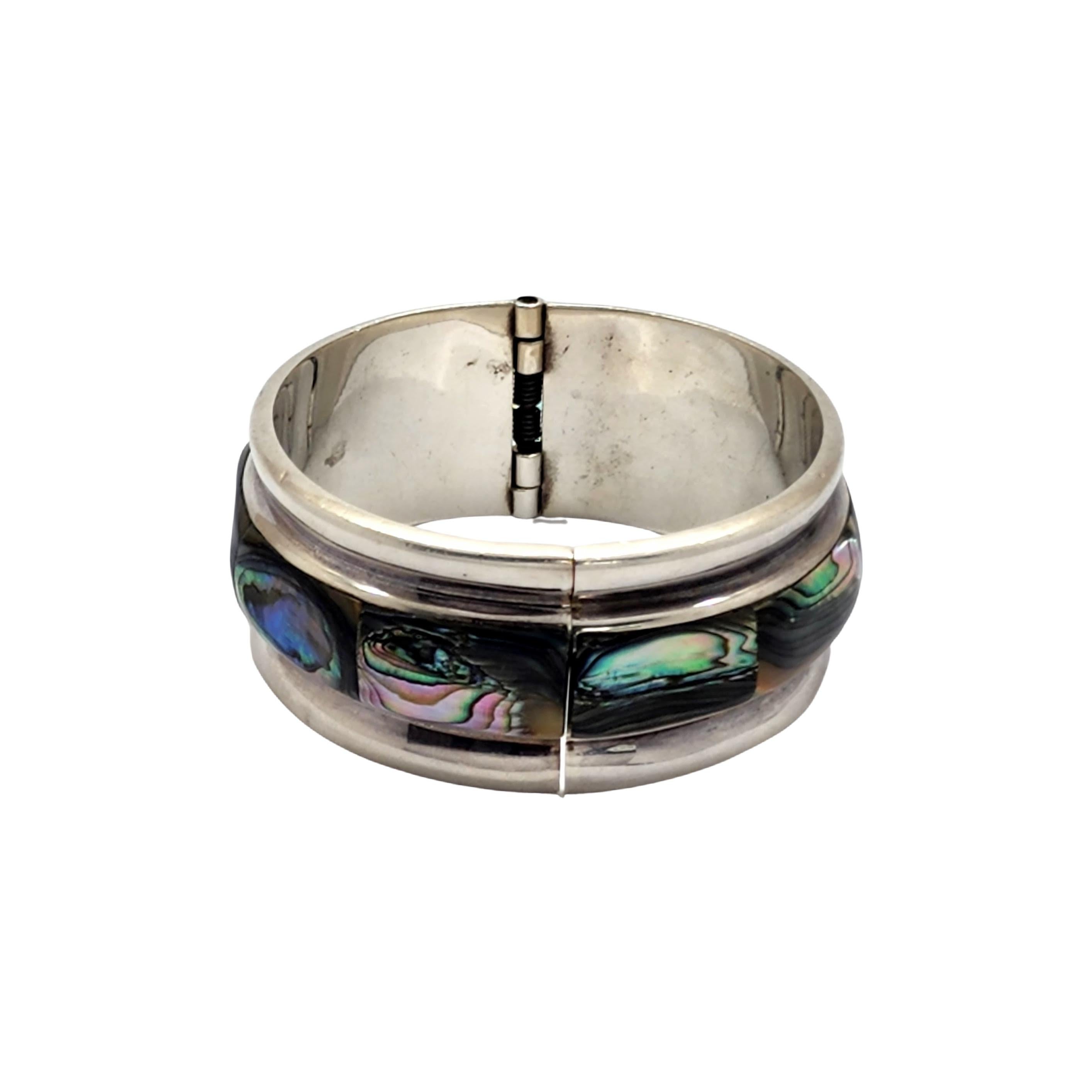 Taxco Mexico sterling silver and abalone hinged bangle bracelet by artisan TA-164.

Beautiful wide bangle featuring rectangular abalone stones at the center. Hinged at back.

Measures approx 7 1/2