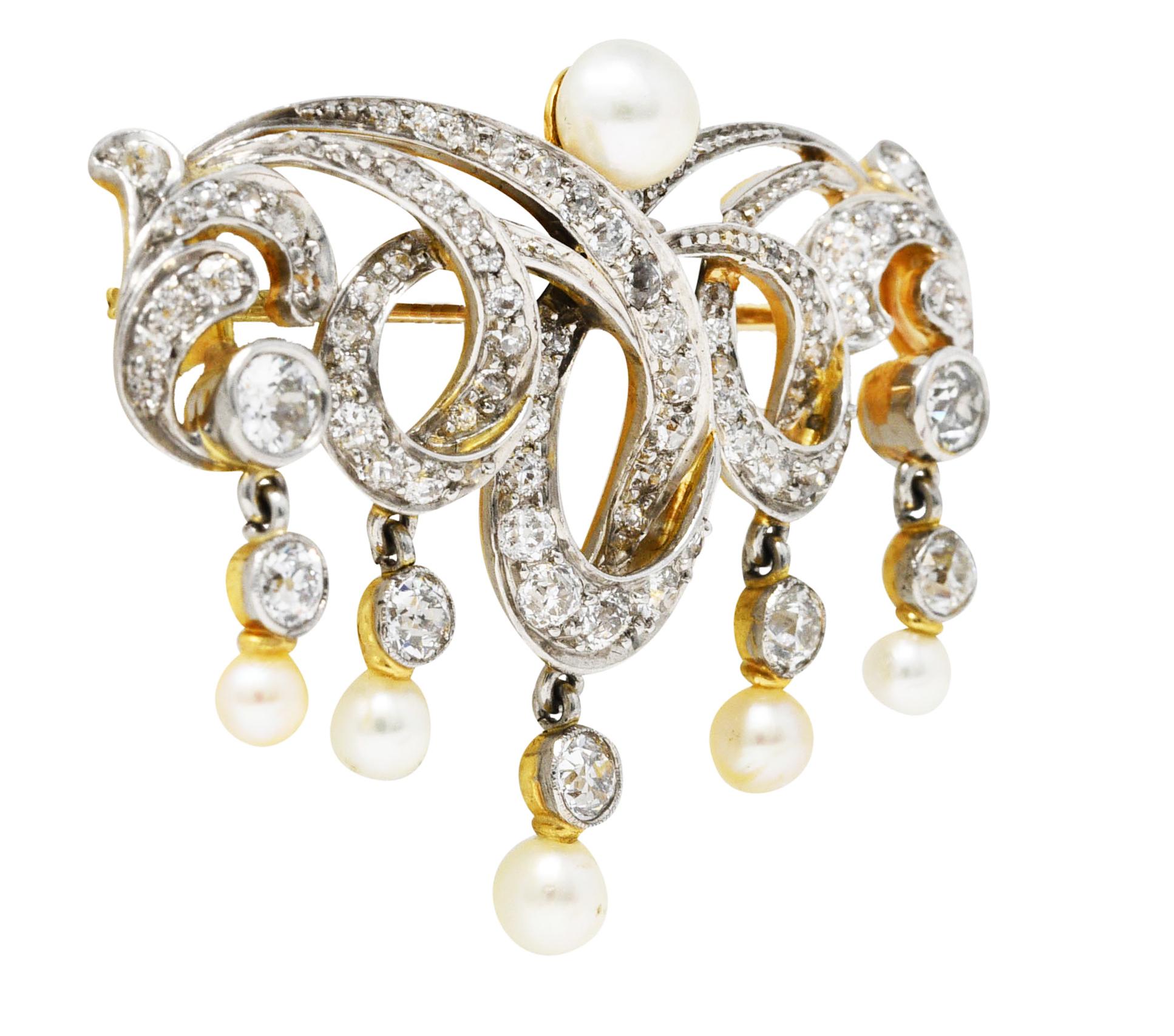Brooch is designed as dynamically formed loops with flourished foliate - oriented East to West. Topped by a 5.5 mm natural pearl - cream in color with moderate iridescence and very good luster. With matching articulated natural pearl drops measuring