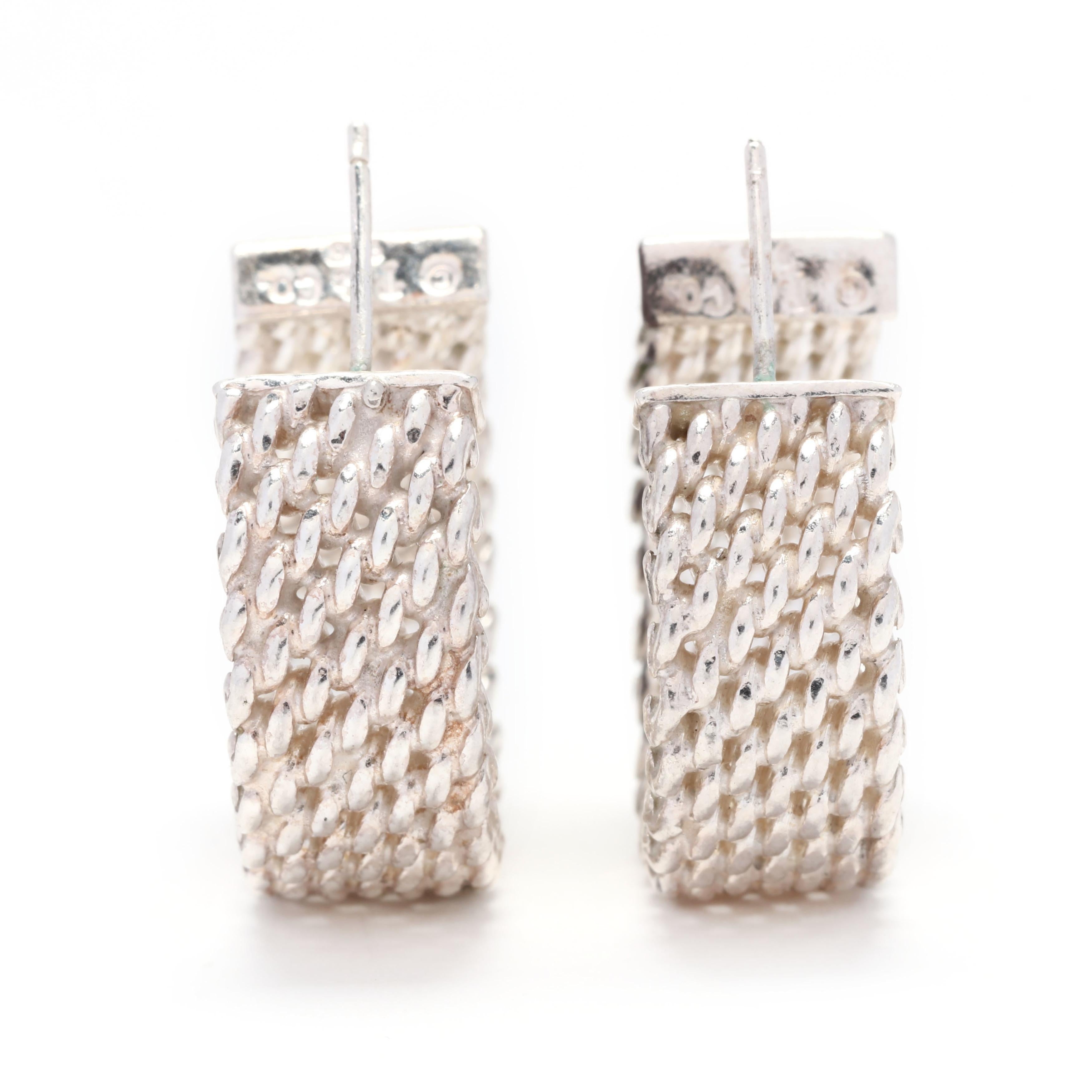 A pair of Tiffany and Company sterling silver Somerset wide hoop earrings. These earrings feature a mesh chain link design with pierced push backs. Please note that these earrings have replacement butterfly backs.



Length: 7/8 in.



Width: 5/16
