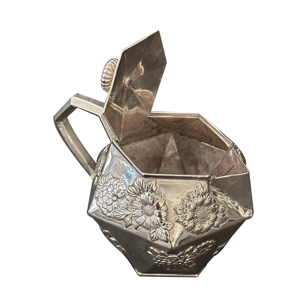 Un exquis service à thé japonais en métal argenté du XIXe siècle, véritable incarnation du charme enchanteur de l'ère Meiji, qui a grandement influencé les designers anglais. Cet ensemble de trois pièces comprend une théière, un pot à lait et un pot
