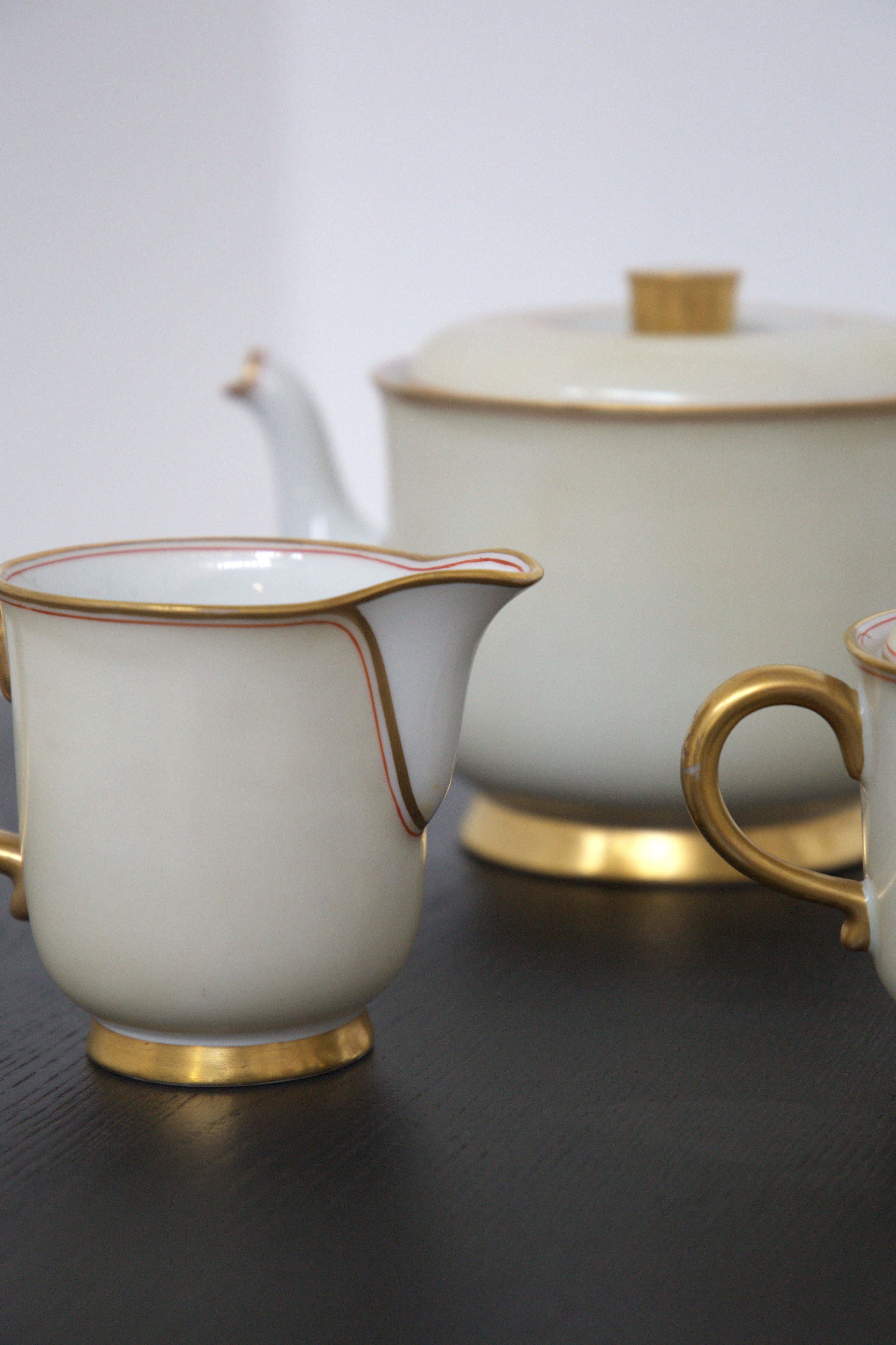 Splendid tea set designed by Gio Ponti for Richard Ginori in the 30's. The set includes a large teapot, a sugar bowl and a cream jug.
The set is made entirely of very fine white ceramic, with the edges embellished with pure gold, and a thin red