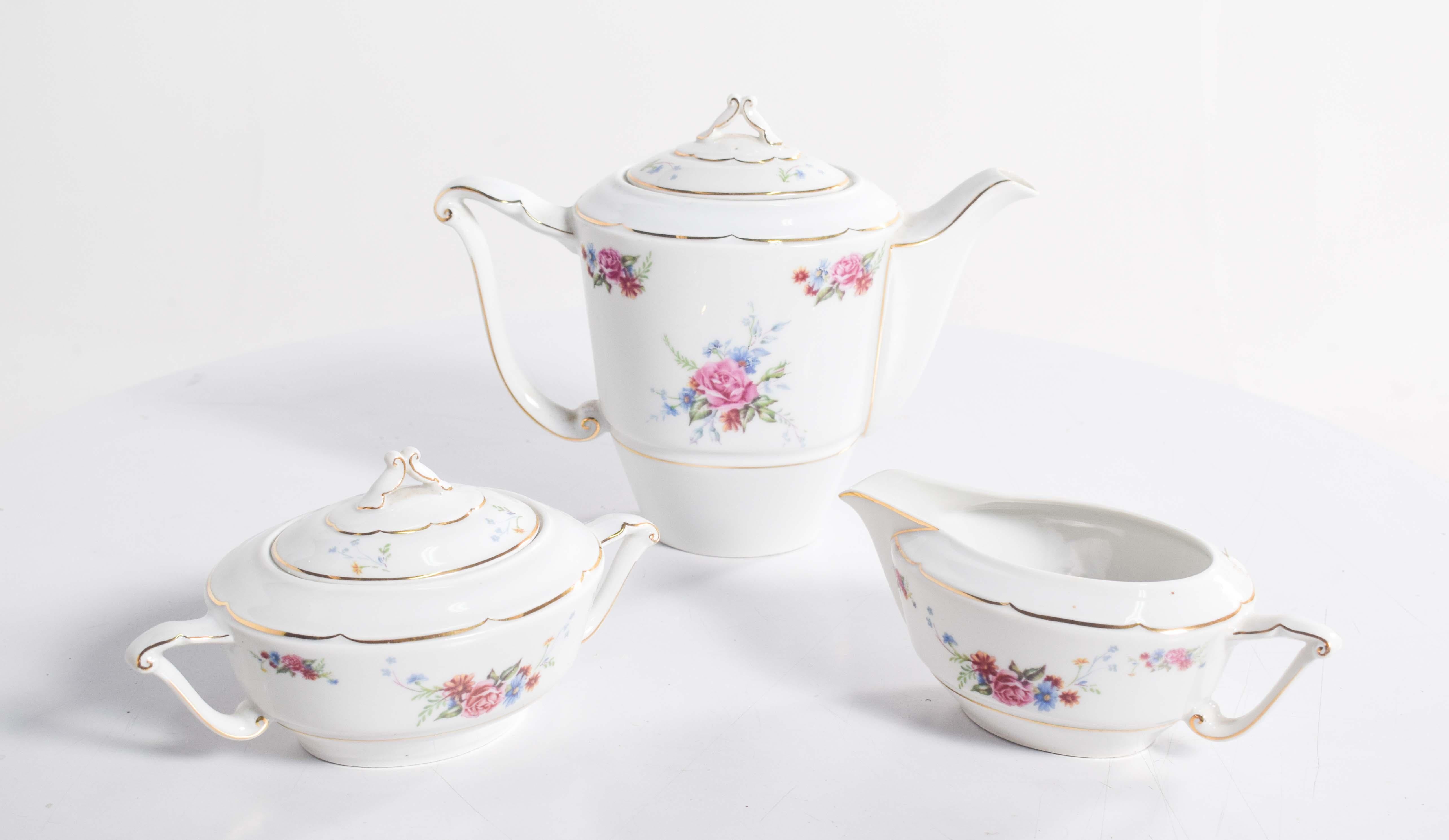 Questo elegante set di porcellana Candal comprende tre pezzi di ottima fattura: una lattiera, una zuccheriera con coperchio e una graziosa salsiera. Ogni pezzo è ornato da delicate decorazioni floreali policrome, con fiori rosa e blu che emanano
