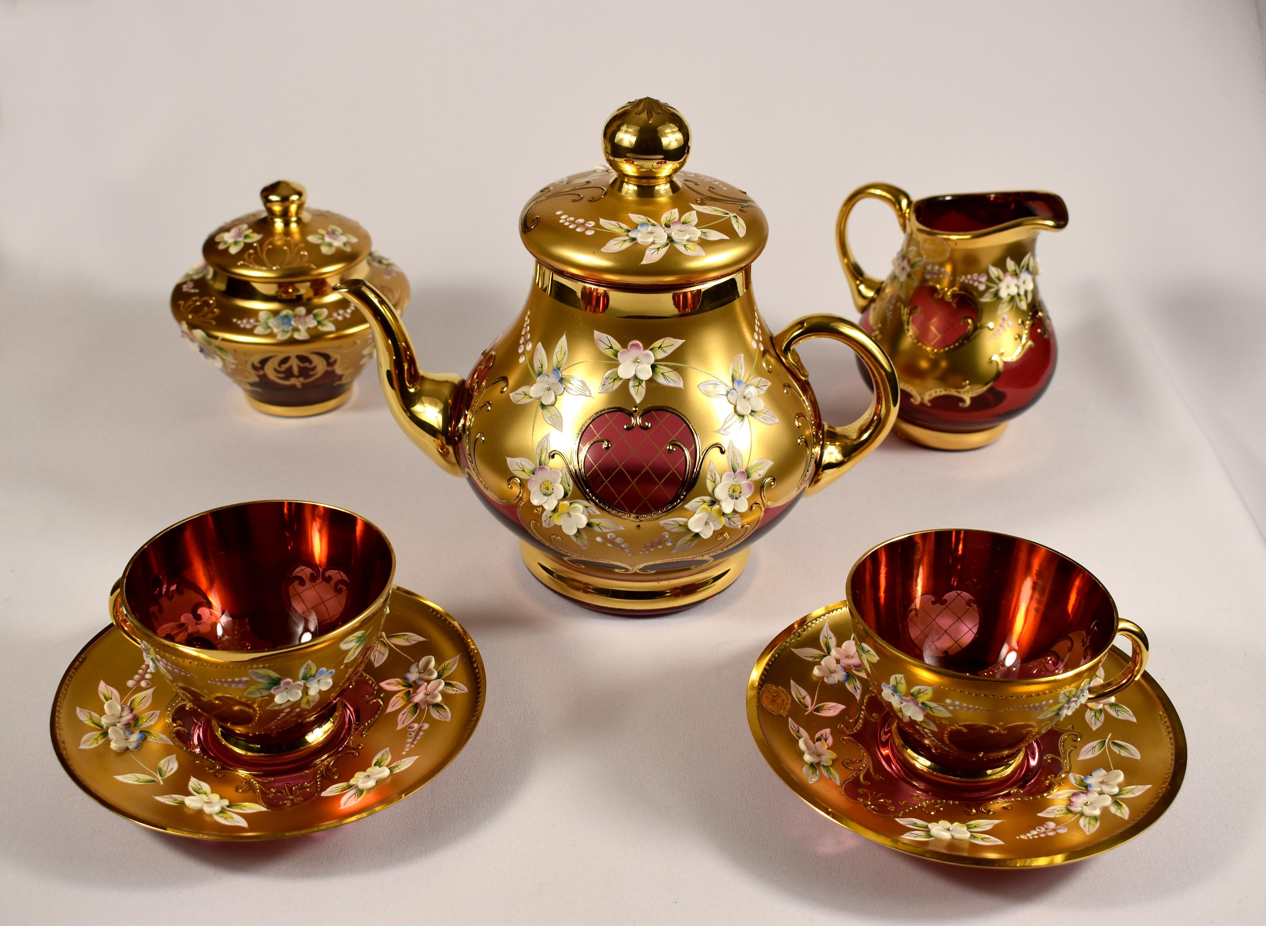 A beautiful tea set for two made of ruby glass decorated with a painting called high enamel. All completed with gilding. This technique was dominant and very popular in glass decoration in the second half of the twentieth century at Crystalex Nový