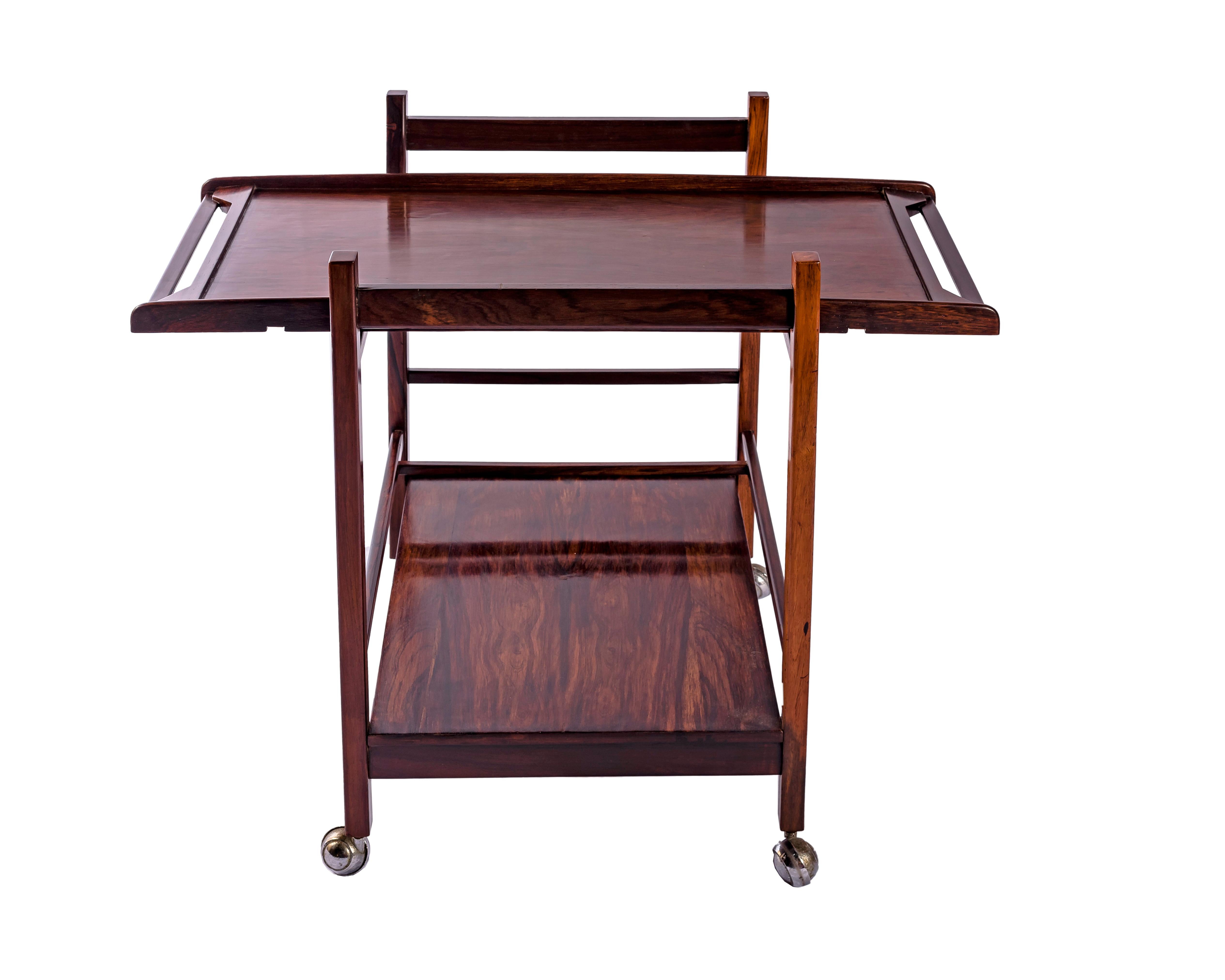 Elegant et fonctionnel, ce chariot à thé de Celina Decorações reflète le raffinement du design domestique brésilien des années 1960. Exécutée en jacarandá richement figuré, sa forme équilibre la clarté géométrique et la chaleur tactile. Les deux