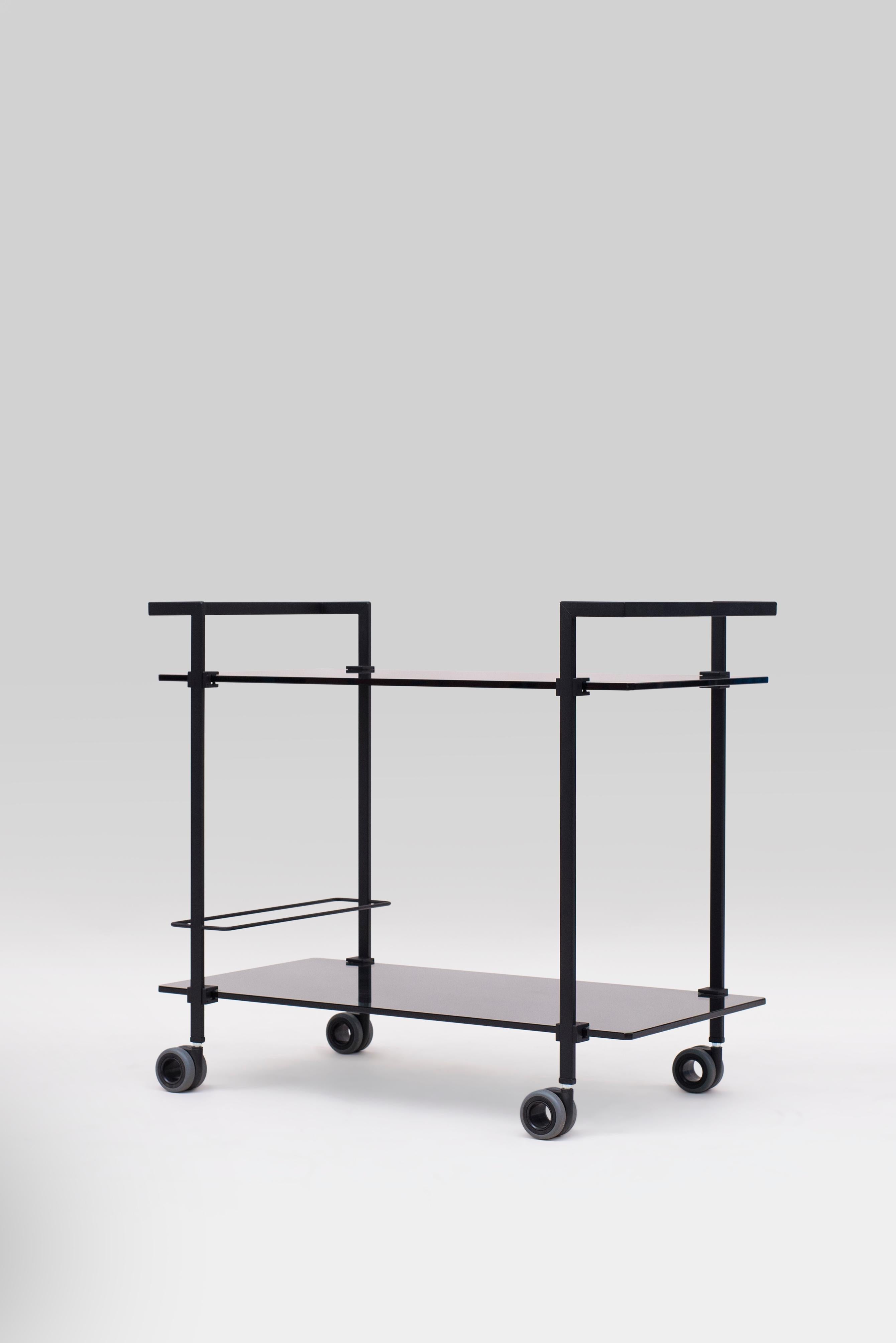 The industrial design tea trolley is designed by Peter Ghyczy and hand made in the atelier of GHYCZY in the Netherlands. The frame is matt black (charcoal) and the tempered glass is grey tinted. The construction of the tea trolley is typical for