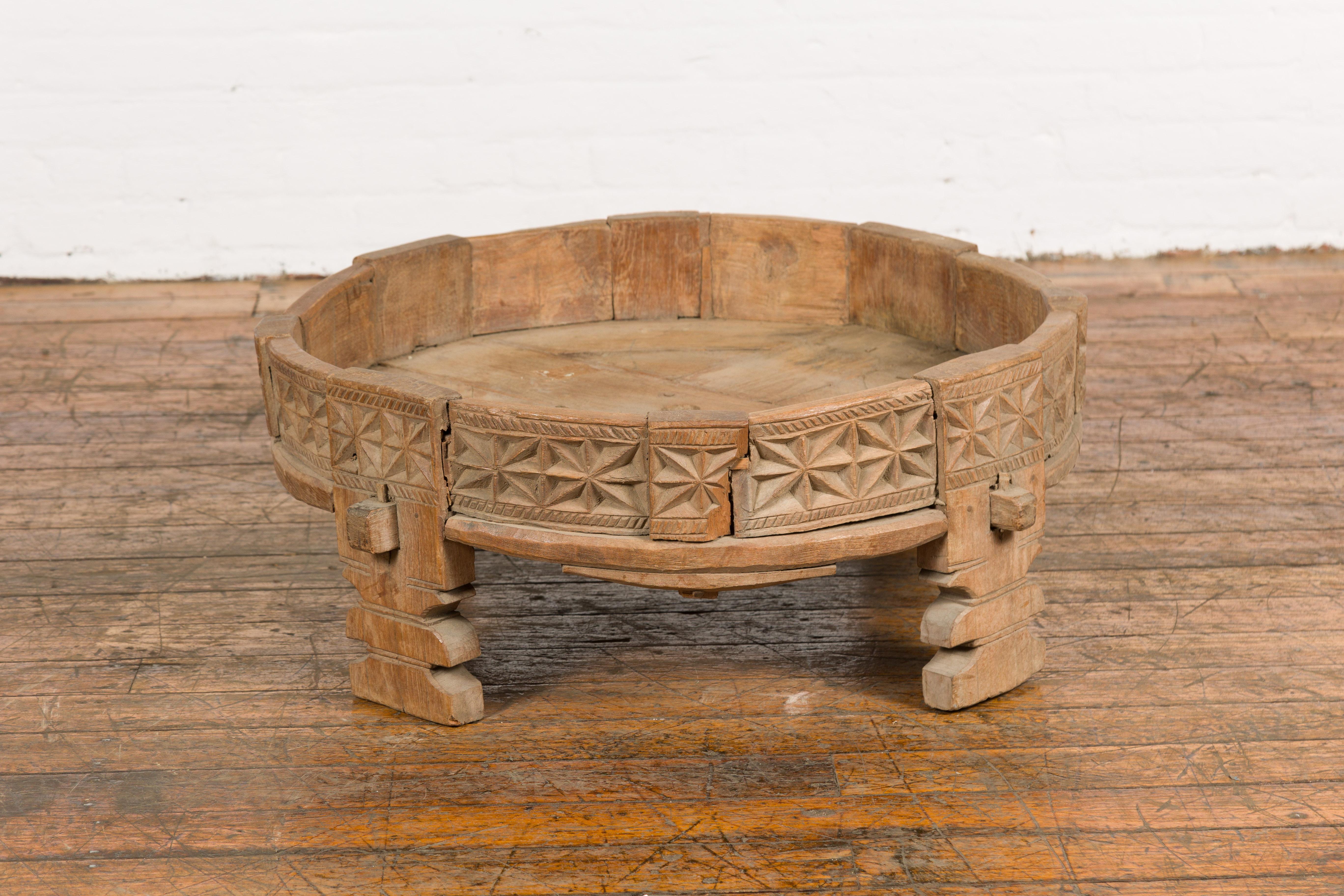 A Tribal Indian rustic Chakki grinder table from the early 20th century with hand-carved geometric motifs, carved feet and weathered patina. Created in India during the early years of the 20th century, this grinder table is called a Chakki.