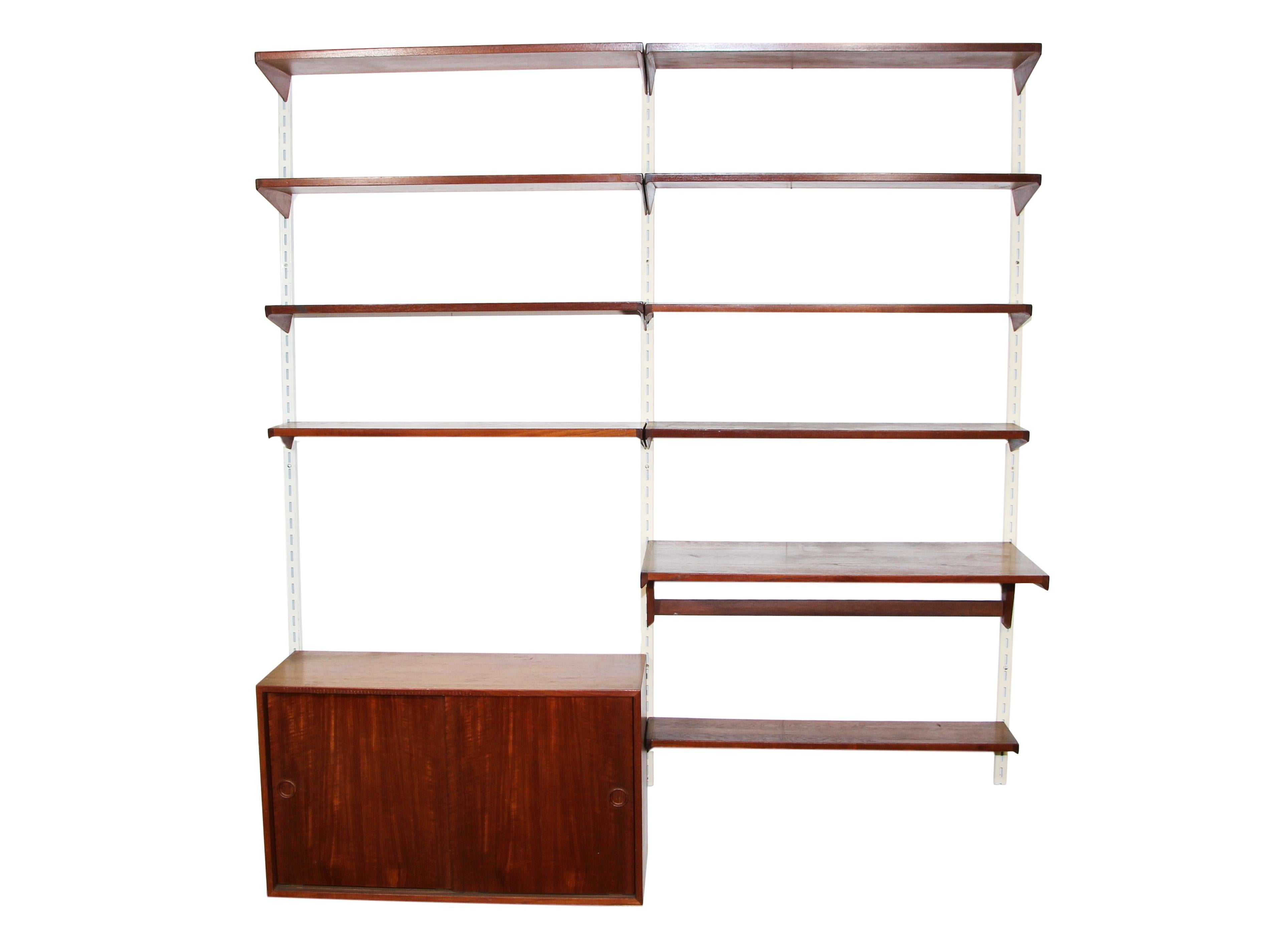 This is a 1960s midcentury Kai Kristiansen dark teak wall unit. Comes with 9 shelves and 1 desk shelf and 1 sliding door cabinet. Metal poles included.

Very good vintage condition. The color has fading on the top of the sliding door cabinet.