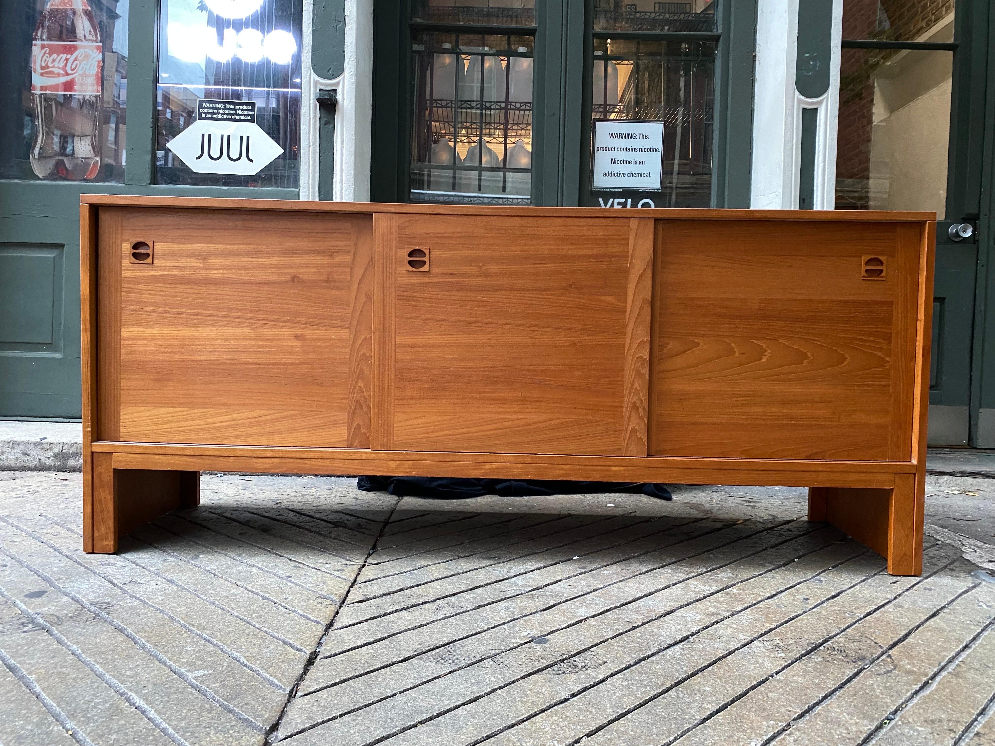 Teak 3 door sliding door Credenza. Doors slide to reveal an adjustable shelf. Each end has one shallow pull out drawer. In nice original condition! Ready to go as is!