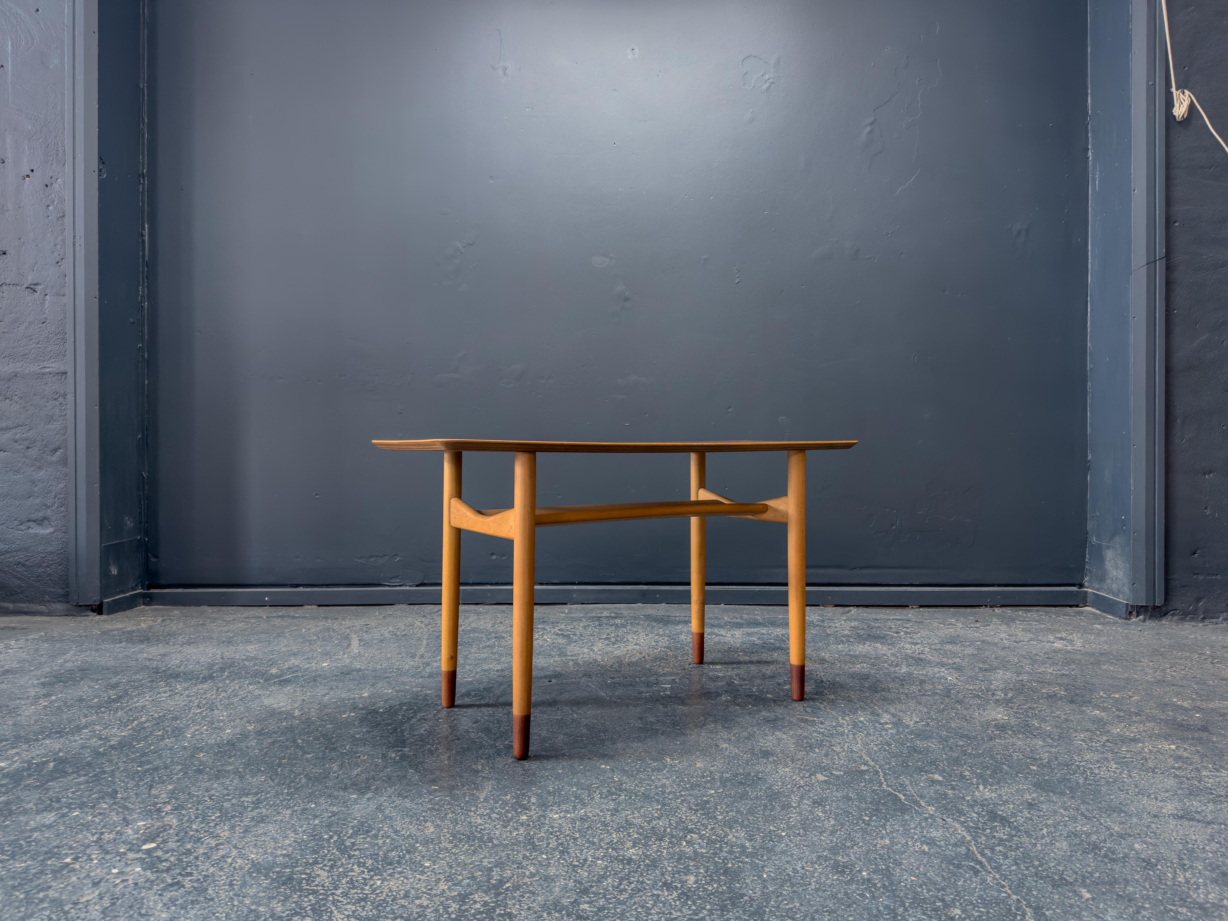 This beautifully crafted Teak and Beech Coffee Table exemplifies the refined simplicity and functional elegance of mid-century Scandinavian design. The tabletop is made from richly grained teak, offering a warm, lustrous surface with subtly rounded