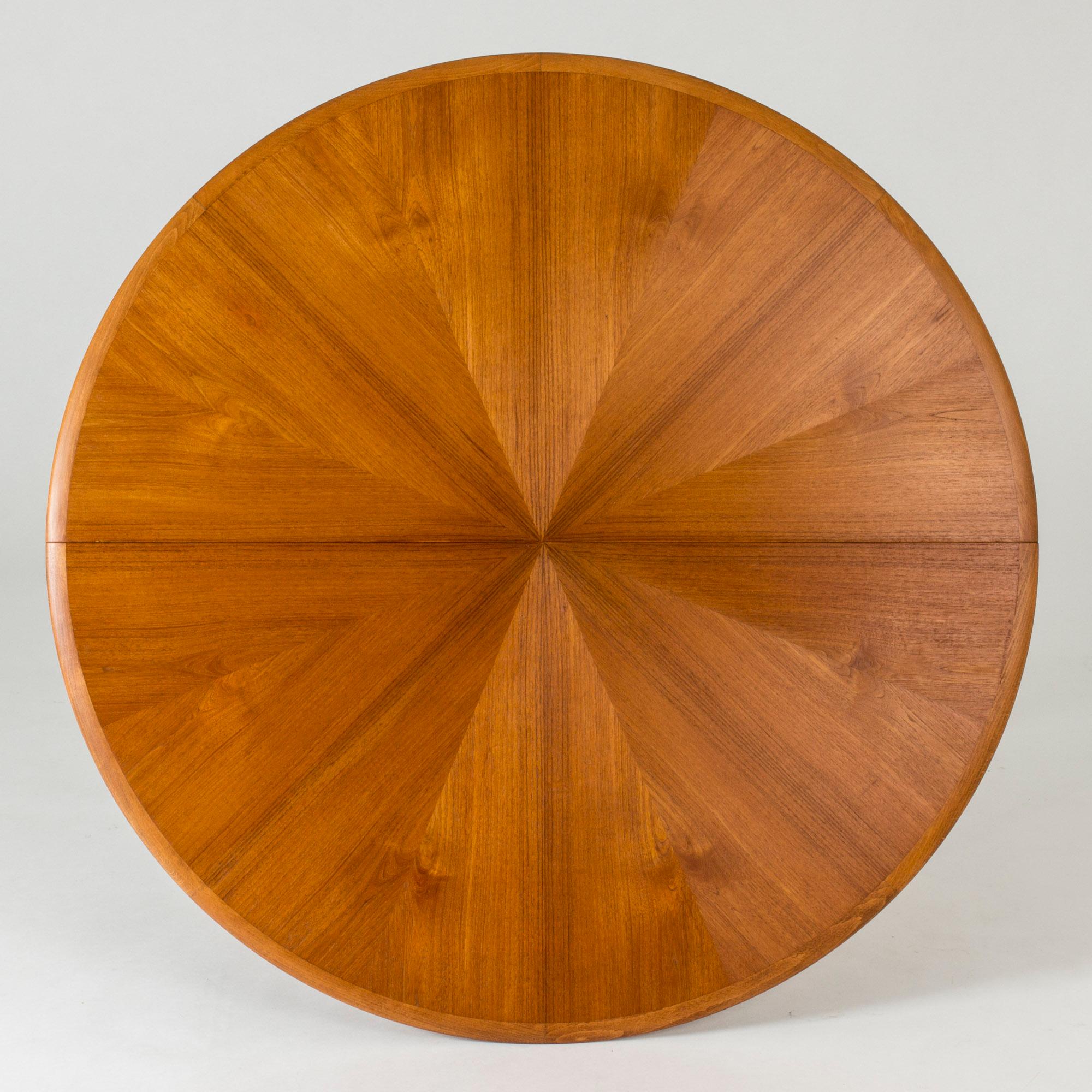 Round teak dining table by David Rosén, with a beechwood piedestal base. Four elegant legs with brass feet extending from the base. Beautiful star shaped veneer on the tabletop.
Three extra leaves make the table very versatile. When three leaves