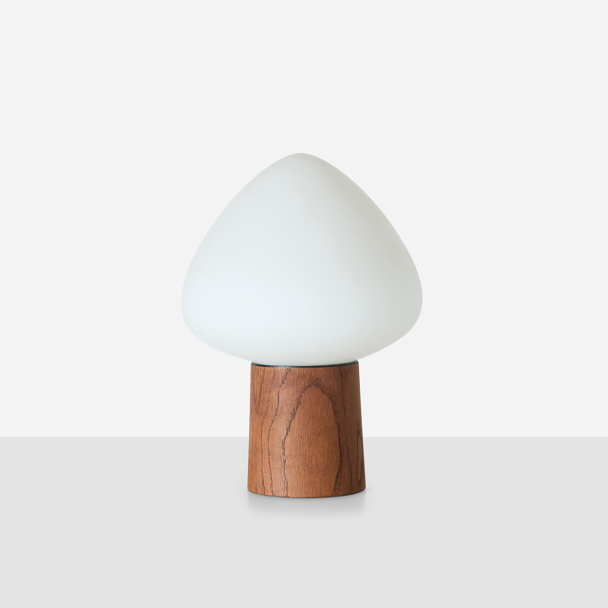 Teak base with mouth-blown frosted white glass shade in acorn form. Retains original label. Wired for US use with E26 bulb and switch at base rear. Tiny nick in teak base near cord, glass shade in excellent condition.