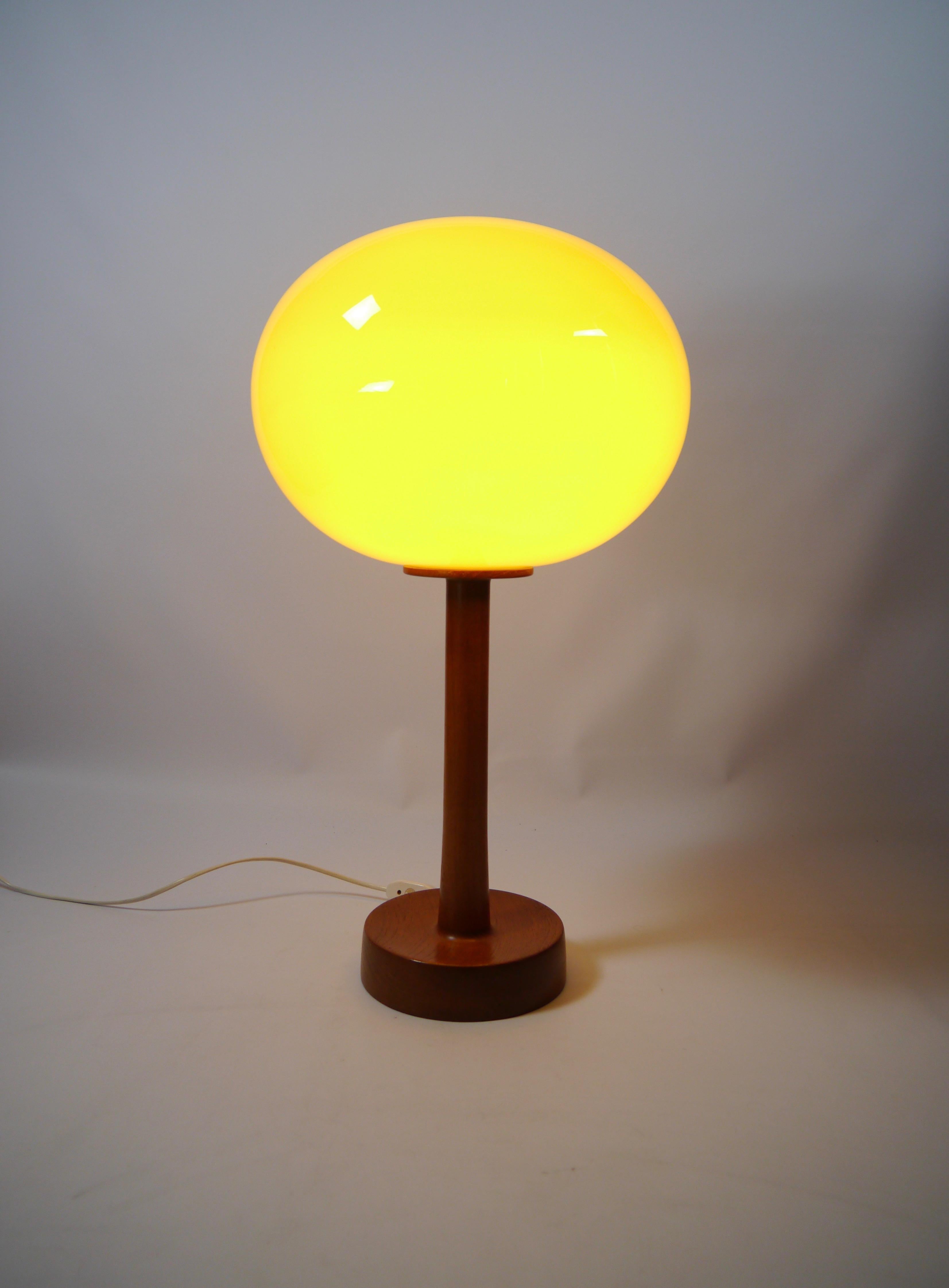 Rare tall teak and glass table lamp designed by Uno & Östen Kristiansson for Luxus Vittsjö. Teak of rich grain and glow, oval shaped yellow glass shade which gives a warm light.