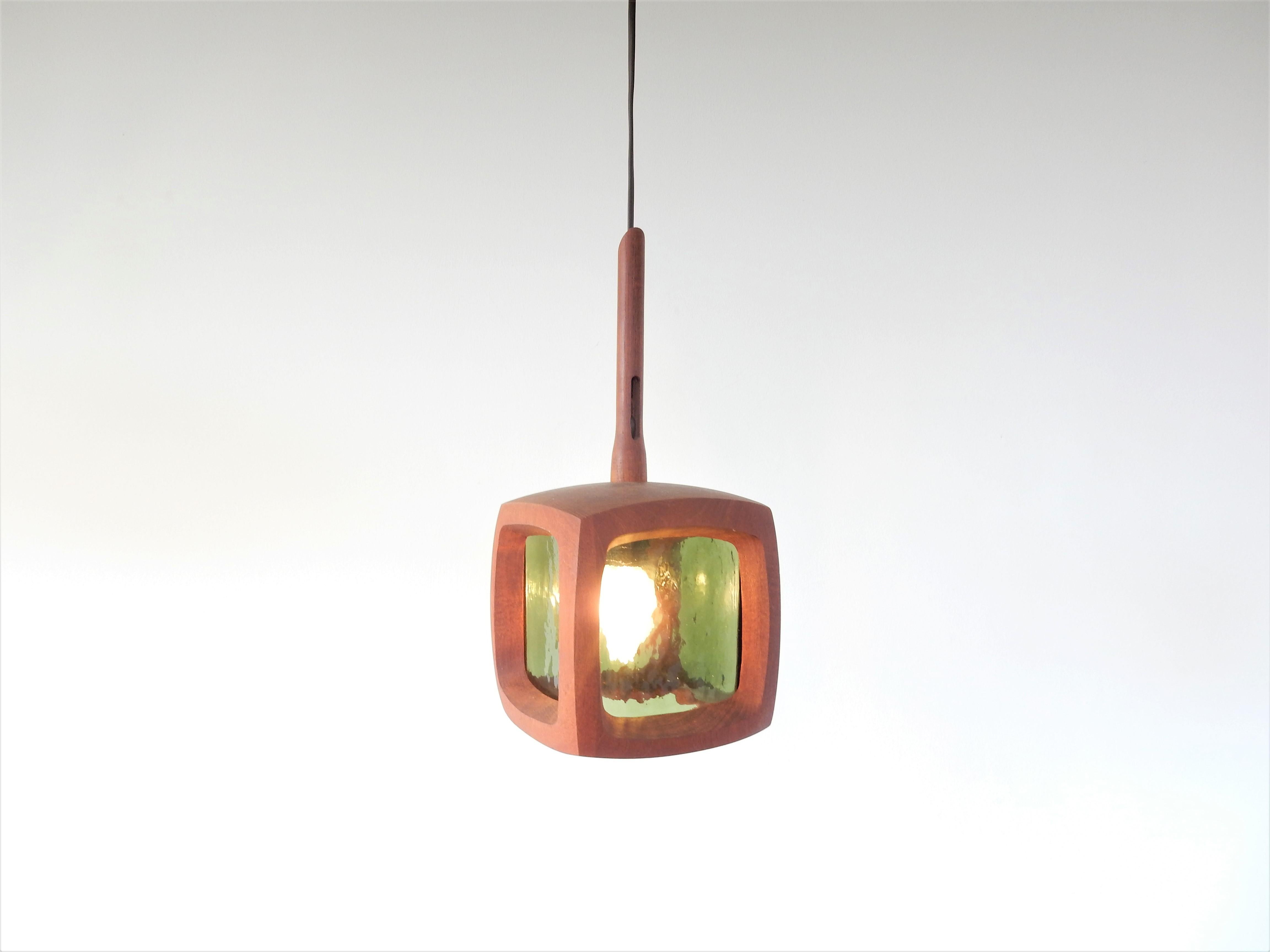 This stunning and not often seen pendant lamp is made in the 1960s-1970s. It is a nicely square shaped lamp made of teak wood and green glass. The lamp is in a very good condition with minor signs of age and use. The shape and material of this piece