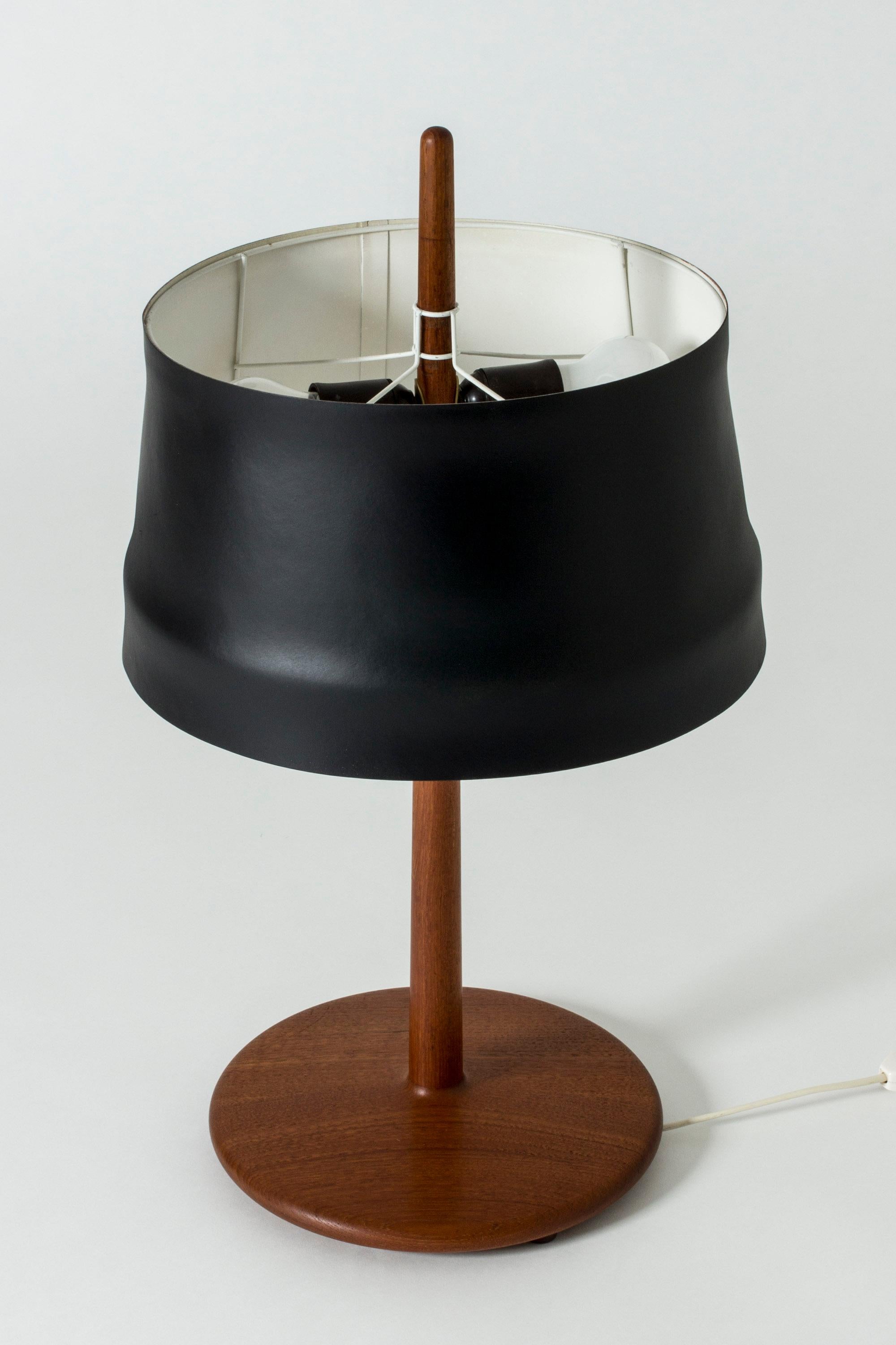 Cool table lamp by Alf Svensson, with a teak base and stem, where the tip of the stem shoots up out of the top of the open shade. Very nice, smooth teak in a streamlined shape. Lacquered black metal shade.