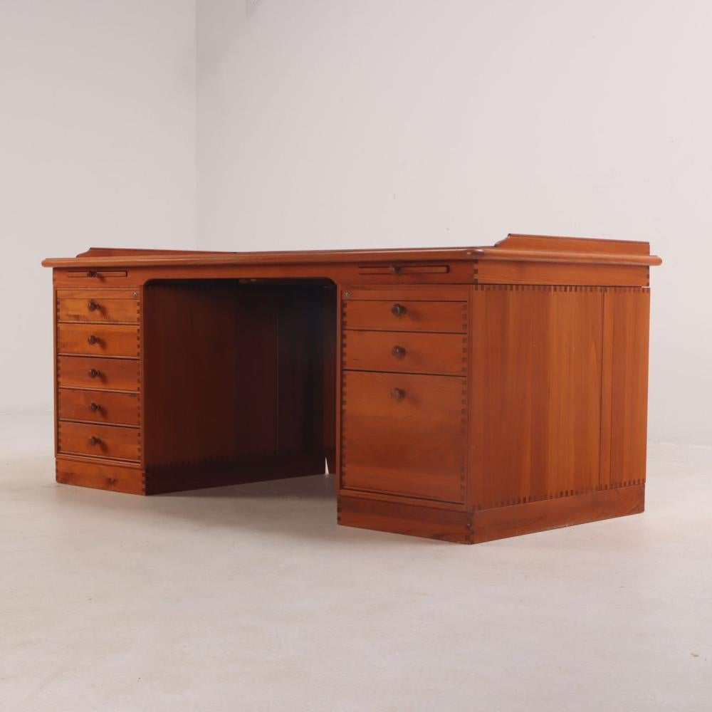An executive sized teak desk by Danish designer Finn Hansen. This piece features a high quality chocolate leather top and pull out trays for maximum tabletop surfaces. Both cabinets feature drawers and doors, with the bottom drawers having filing