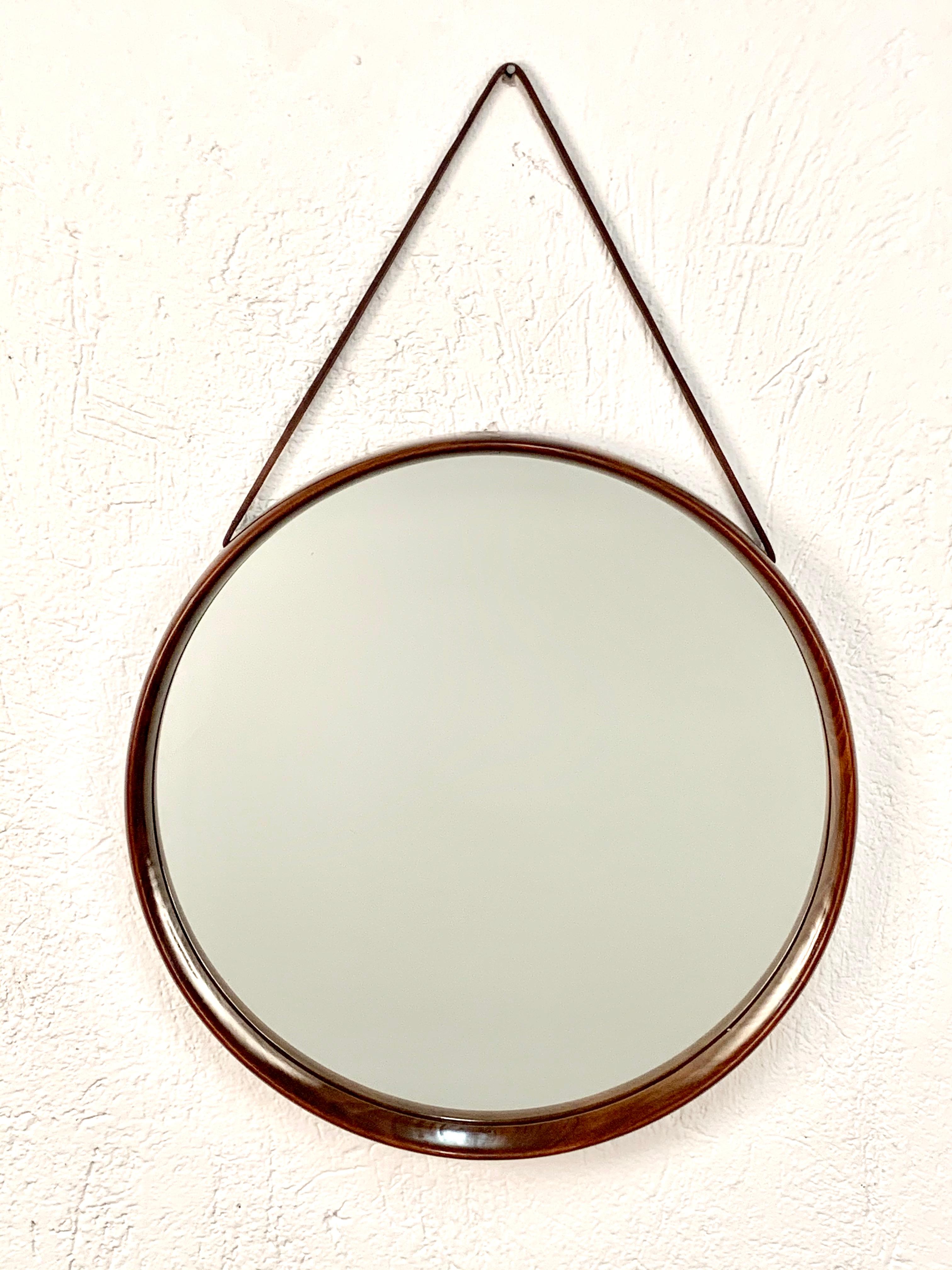 Swedish mirror by Uno & Östen Kristiansson for Luxus in teak with a leather hanging strap. 

The frame circulates the glass and is made out of different pieces of wood which were interlaced with each other, creating a beautiful variety of colours