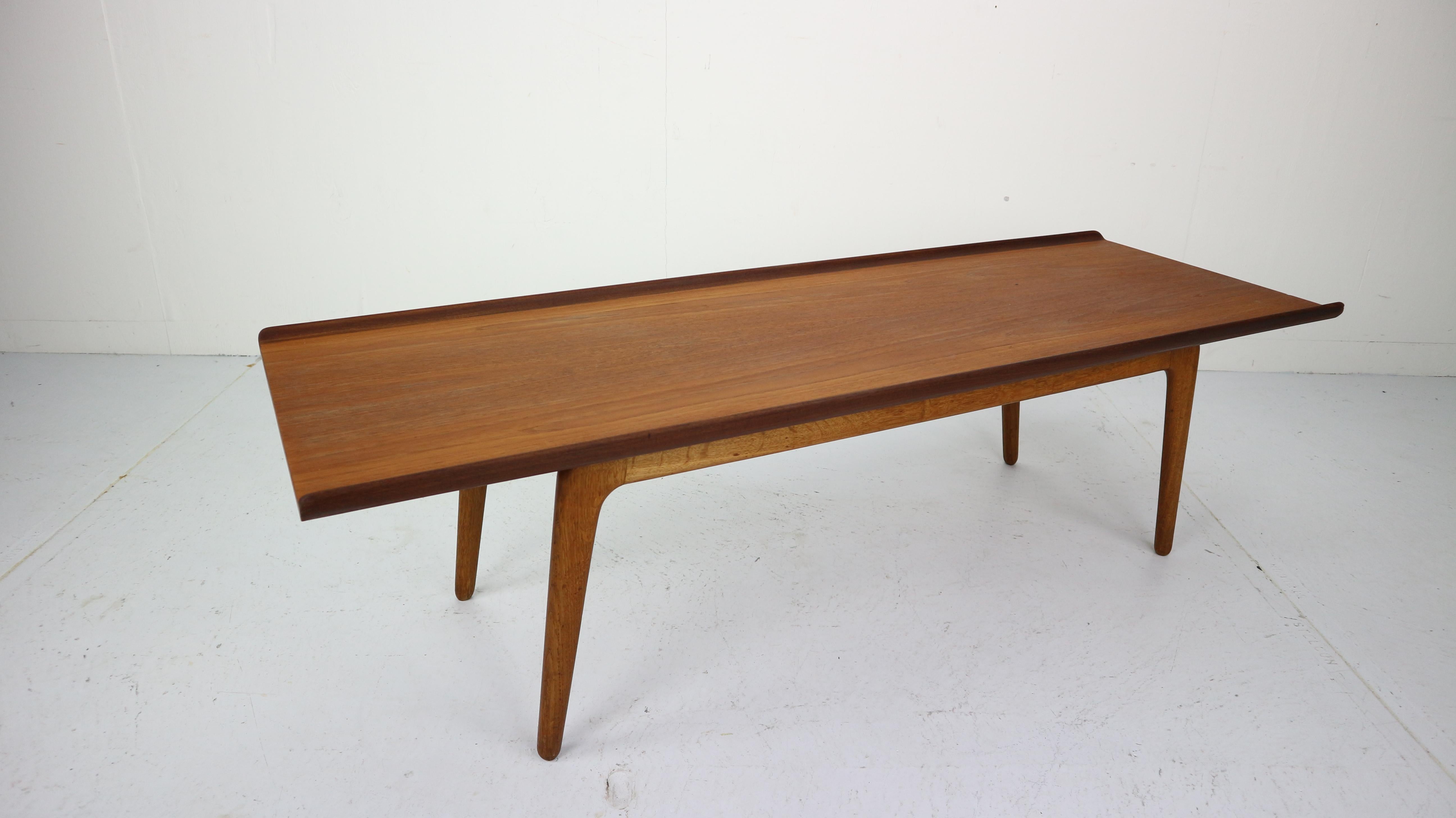 This original solid coffee table in teak with 'boomerang' oak legs was designed by the Danish designer Aksel Bender Madsen and manufactured by Bovenkamp in The Netherlands in the 1960s. The tabletop features very elegant curved edges on the long