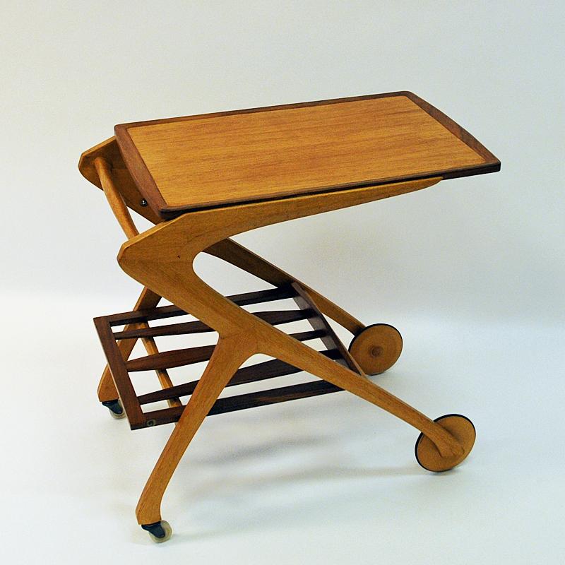 Lovely serving trolley of teak and oak by Arne Fregnell for NC-Möbler in 1959, Sweden. The trolley has large decorative front wheels and smaller back wheels. Removable teak shelf that is also adjustable from flat to upright tilted position and