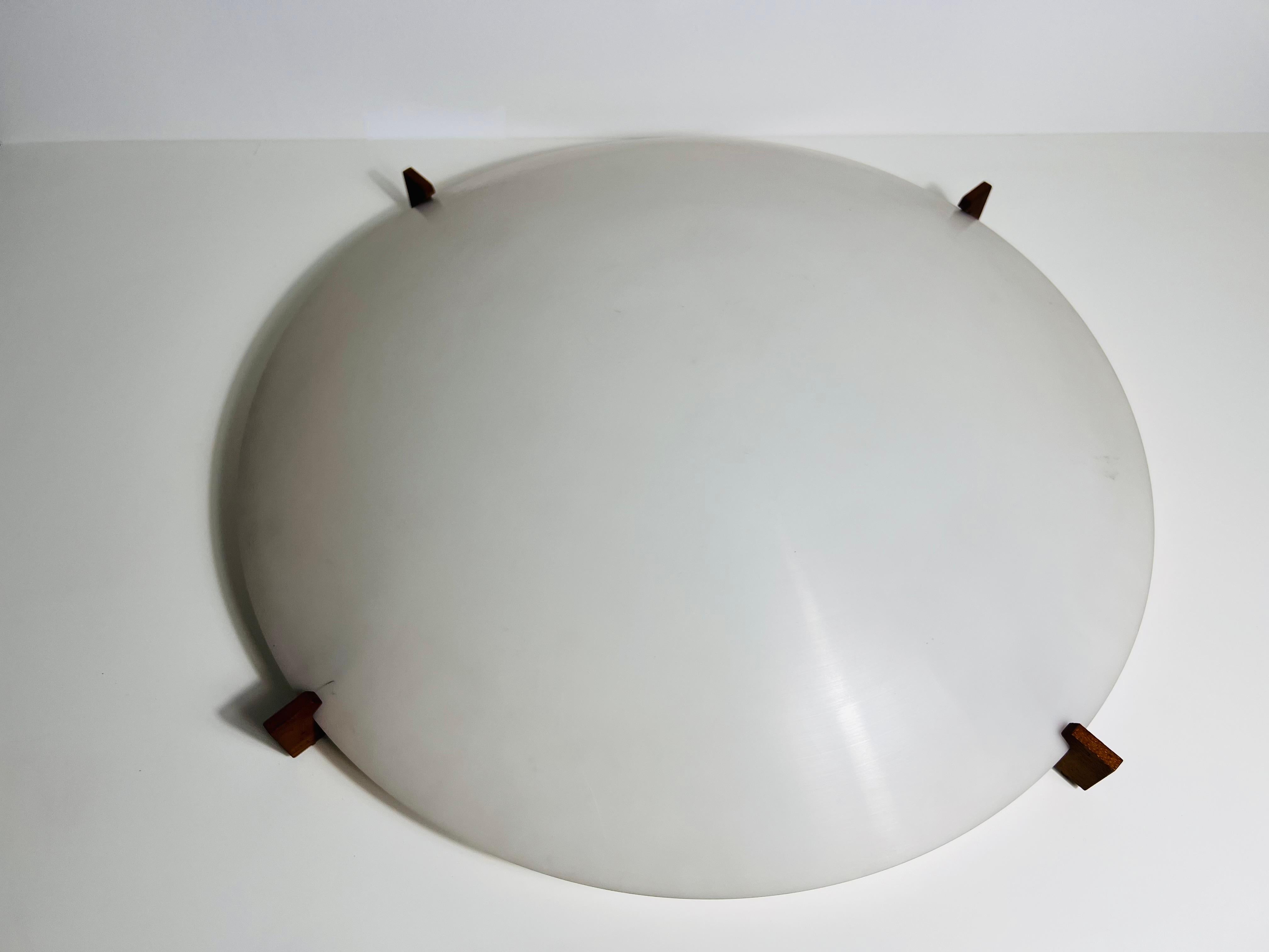Conçue par les célèbres designers suédois Uno et Östen Kristiansson pour Luxus dans les années 1960, cette exceptionnelle lampe à encastrer incarne l'élégance du modernisme scandinave. La pièce maîtresse est un abat-jour rond et bombé en plexiglas