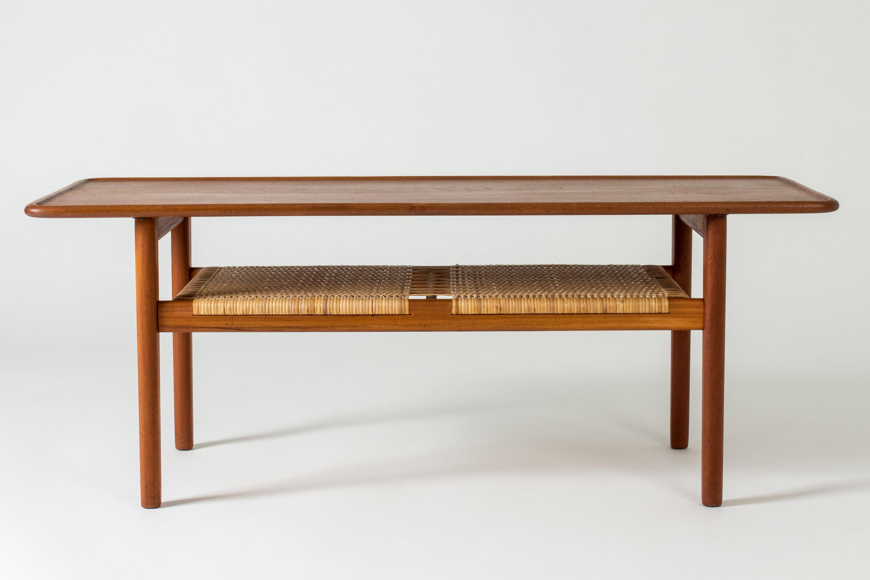 Beautiful teak coffee table with a rattan shelf by Hans J. Wegner. The warm teak nuance contrasts nicely with the blonde rattan.