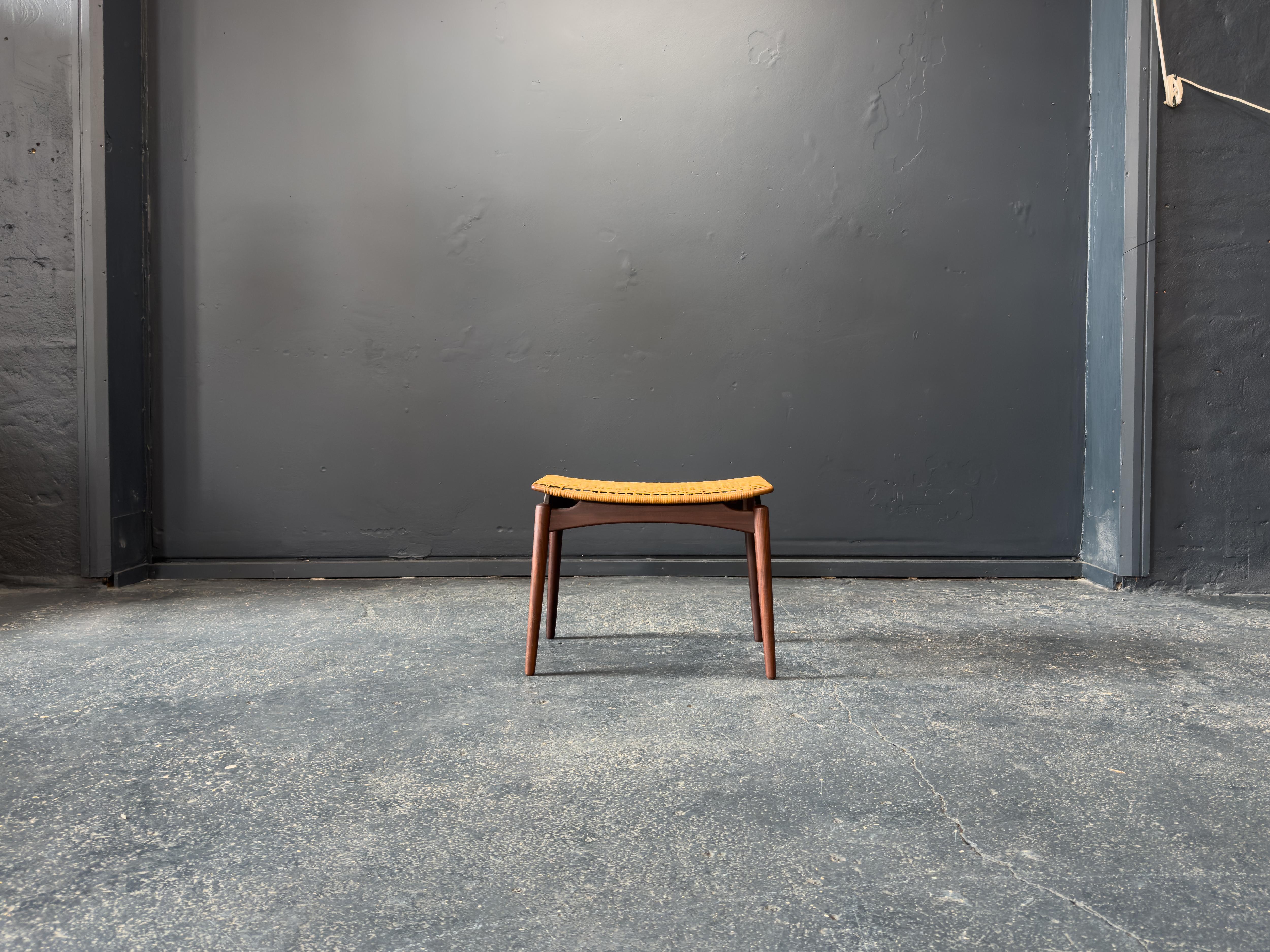 Questo sgabello con pouf di Ølholm Møbelfabrik è un esempio di fusione armoniosa tra materiali naturali e design scandinavo pulito. Caratterizzato da una solida struttura in teak, il pezzo mette in risalto le ricche tonalità dorate e le venature