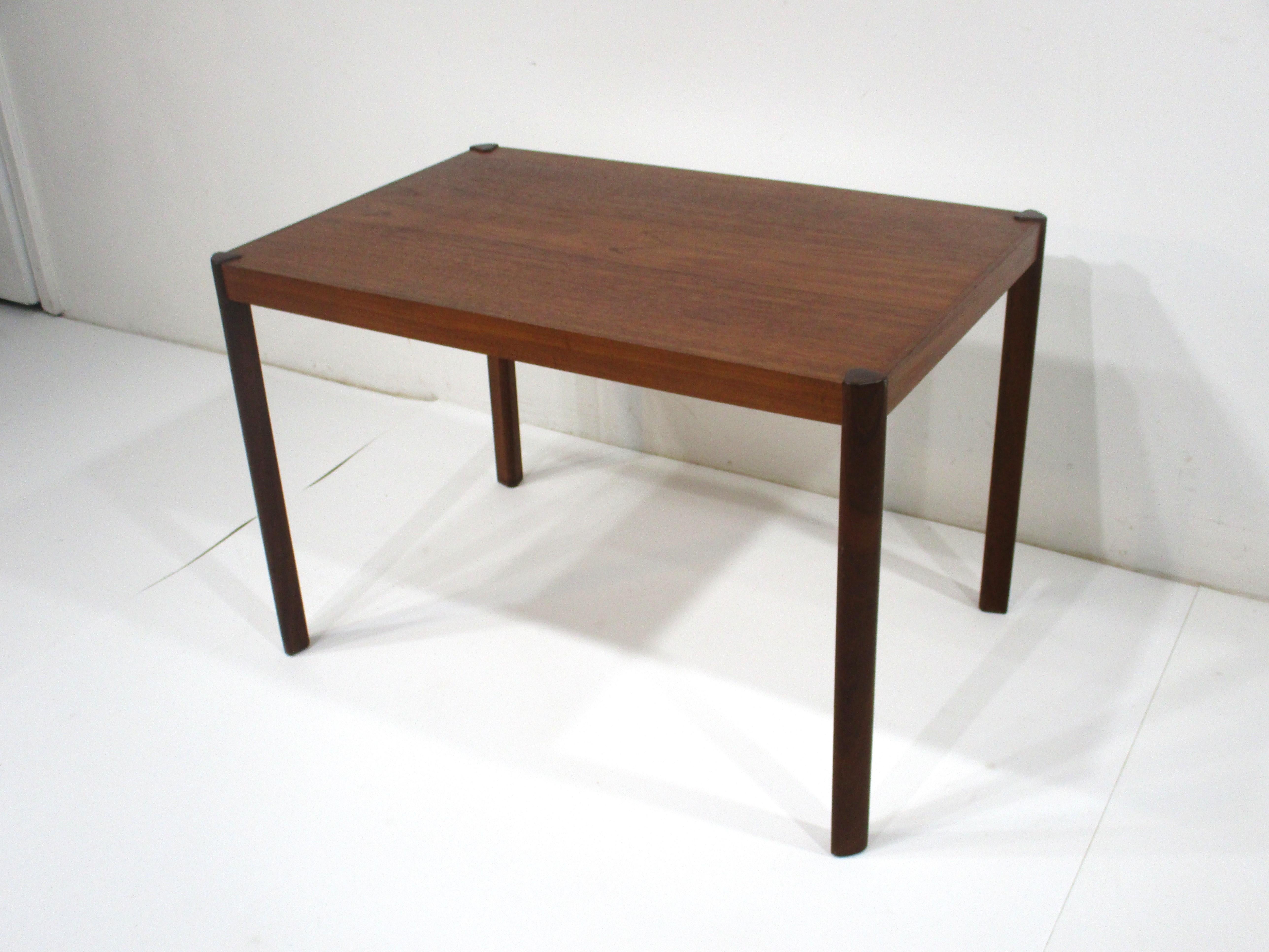 A teak wood side / end table with nice triangled shaped solid rosewood legs with the tops anchoring each corner . A simple but elegant form perfect for that special spot made in Denmark and designed in the manner of Magnus Olesen .  