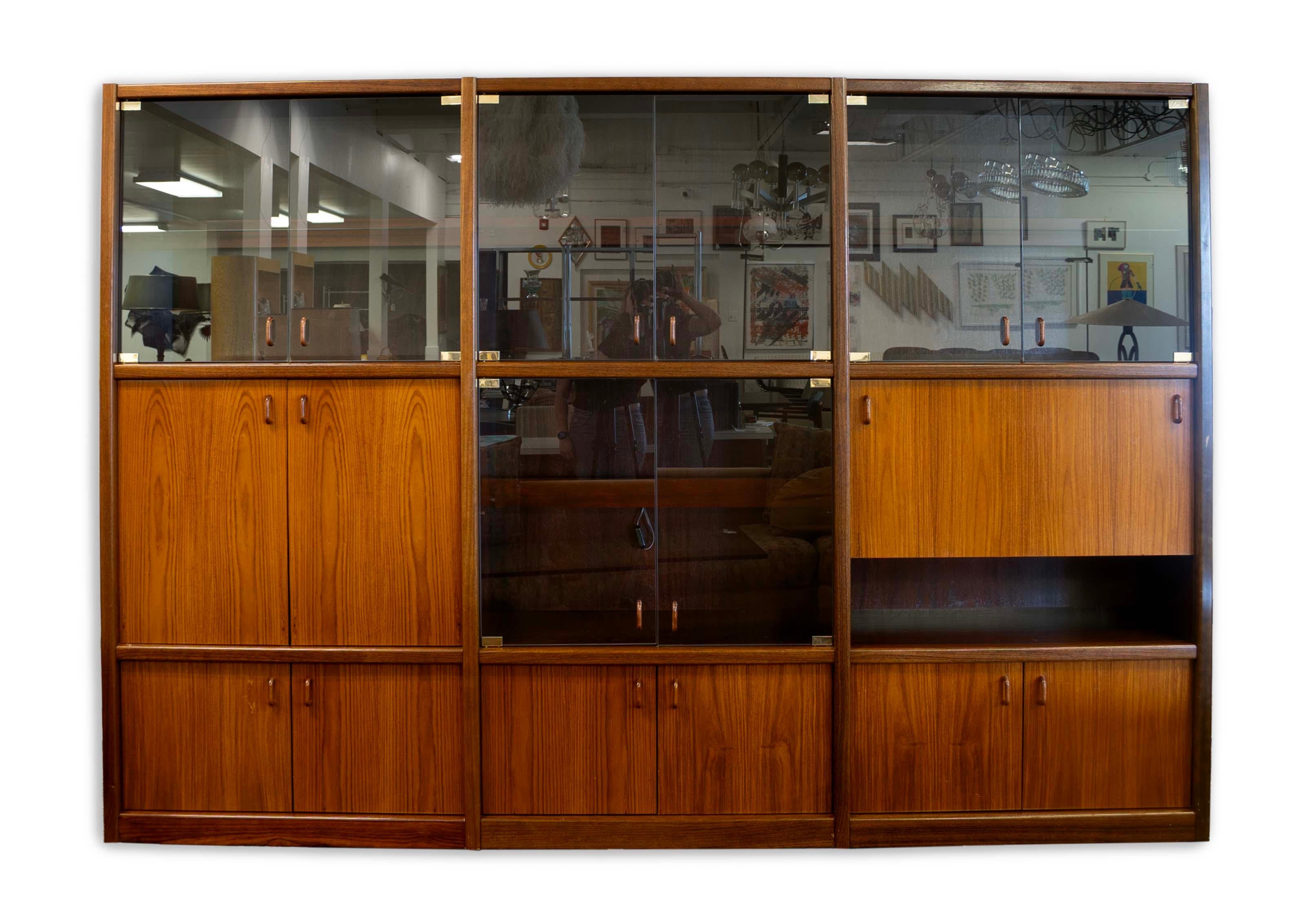 Elegante e funzionale, questa parete attrezzata in teak e palissandro con scrivania incarna il design moderno di metà secolo. Realizzato con un ricco teak e un sorprendente palissandro, questo mobile offre un ampio spazio di archiviazione grazie
