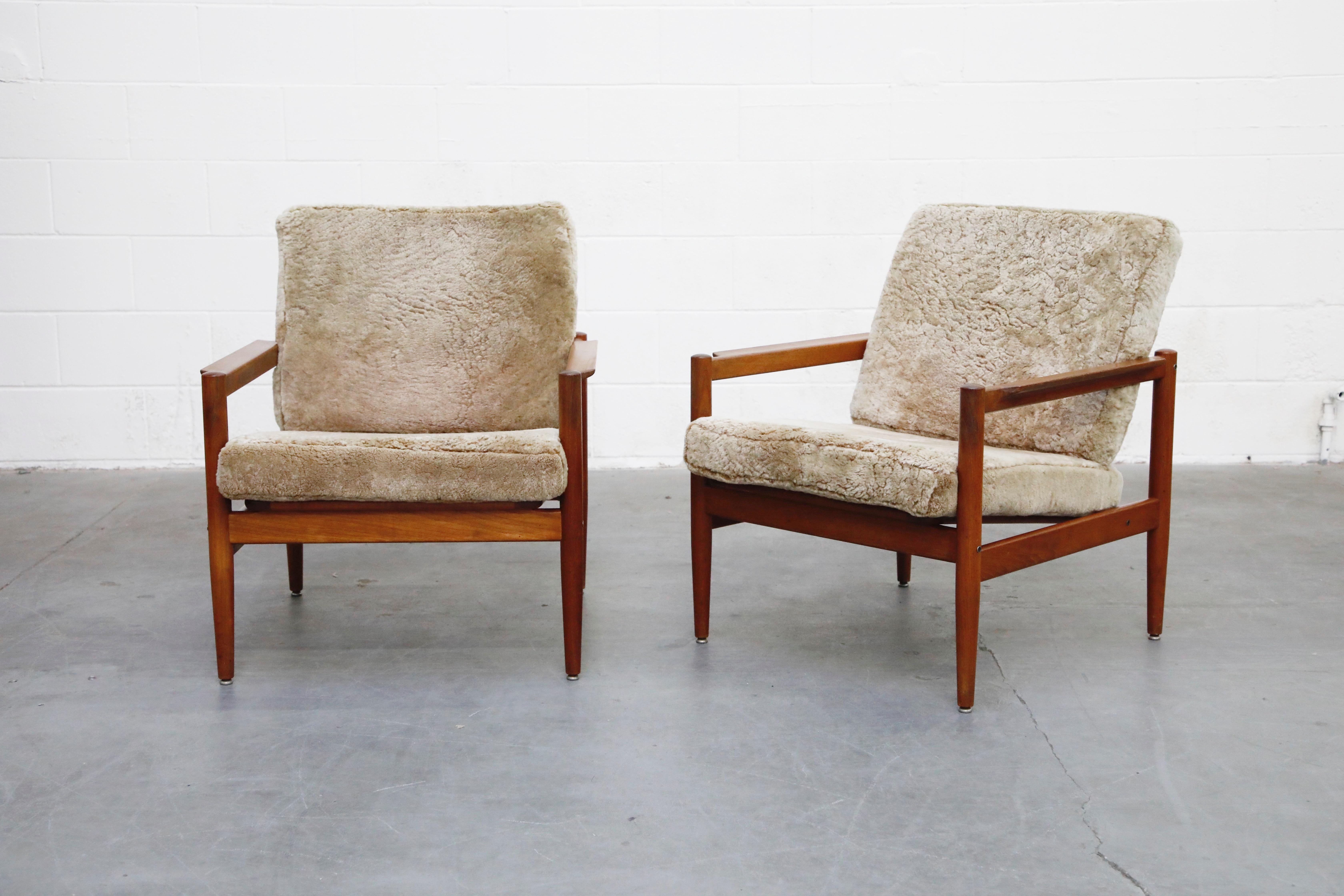 This pair of solid teak and shearling fur cushions lounge chairs are by Børge Jensen & Sønner for Bernstorffsminde Møbelfabrik. Featuring slatted wood backs, sculpted arms and nubby wooly shearling fur cushions, this is the perfect easy chair option