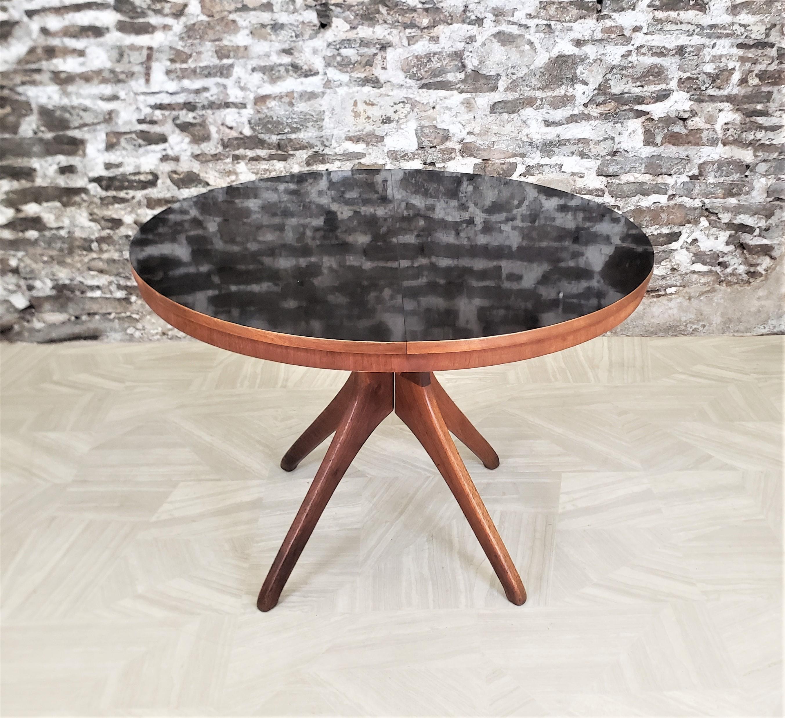 This round or oval, with the leaf, dining table is unsigned, but presumed to have originated from Finland and date to approximately 1950 and done in the period Mid-Century Modern style. The table is composed of teak with a black arborite inset top.