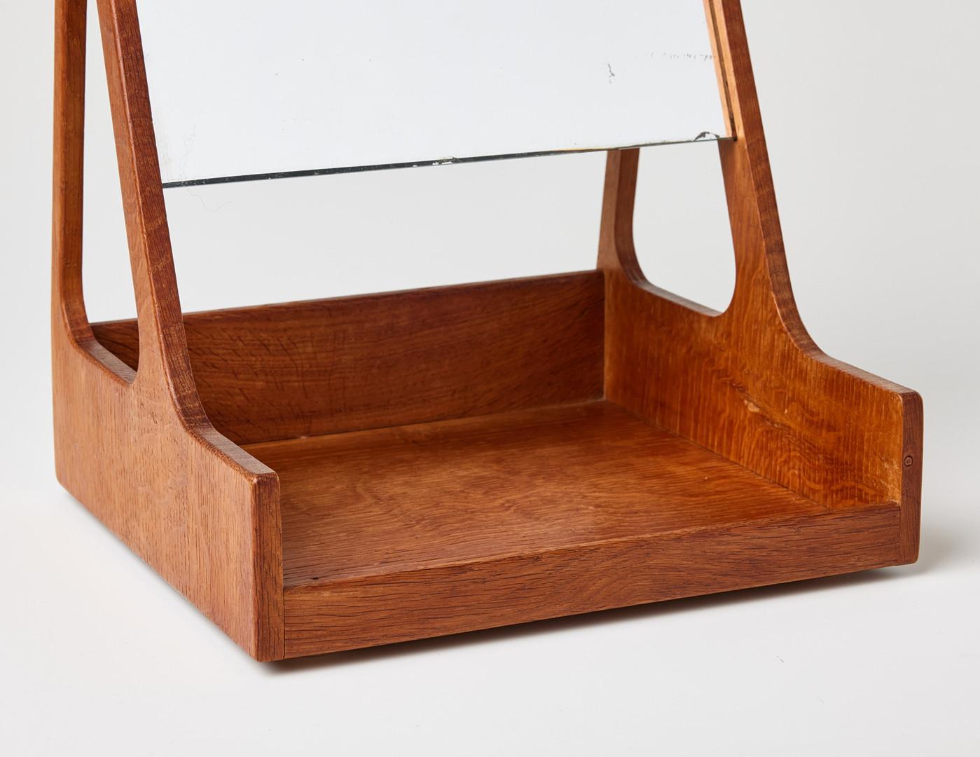 This elegant beauty box table mirror, designed by the legendary Hans J. Wegner and manufactured by RY Møbler, epitomizes Scandinavian mid-century design. With its minimalist teak frame, slide-in mirror, and practical tray base, this piece perfectly