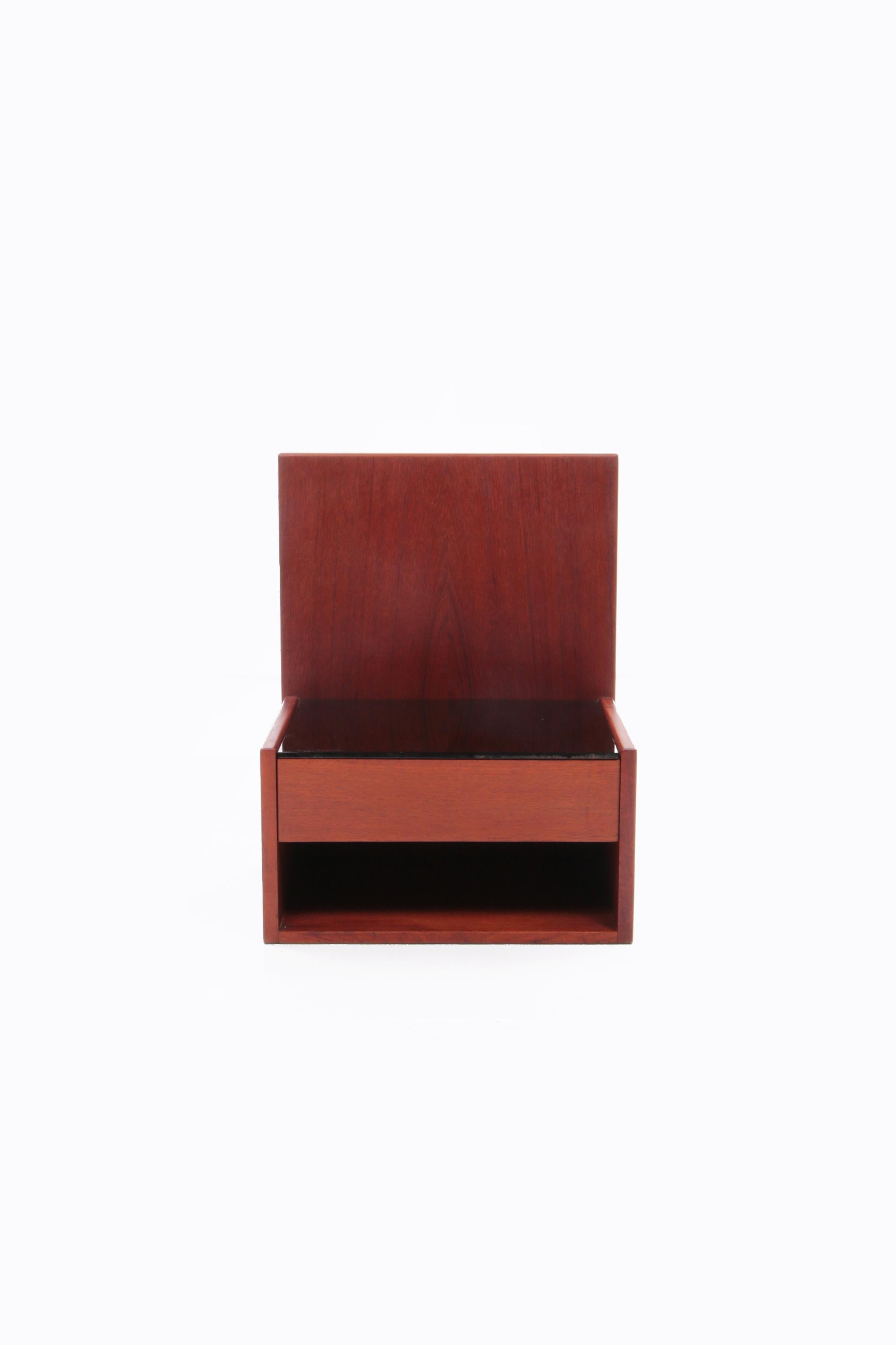 Beautiful bedside table to hang on the back, two attachment points are made. Beautiful teak with a hidden drawer and a smoked glass plate. Another beautiful sleek design by Designer Hans J.Wegner.

Marked on the back, see photo.
Hans J. Wegner

One