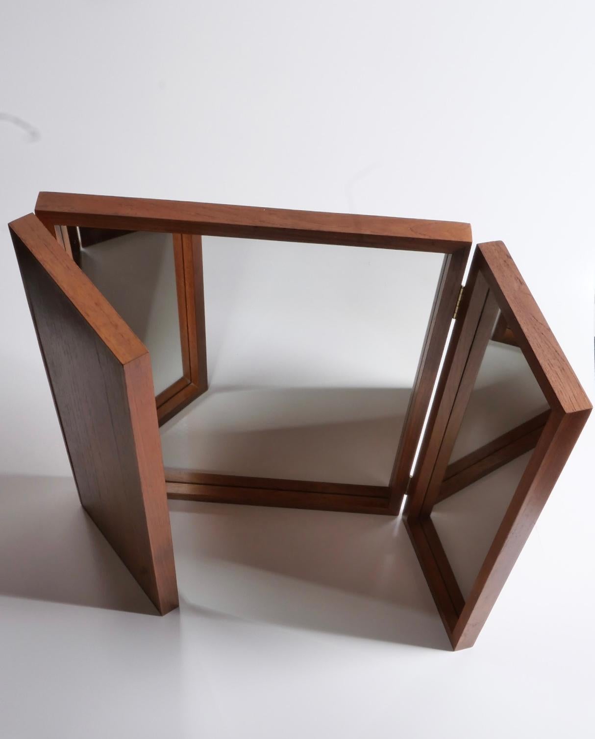 Magnifique miroir pliant à poser ou à accrocher au mur, de Kai Foldes. Cadre en teck massif avec charnières en laiton. Fabriqué au Danemark par Aksel Kjersgaard, années 1960. Excellent état.