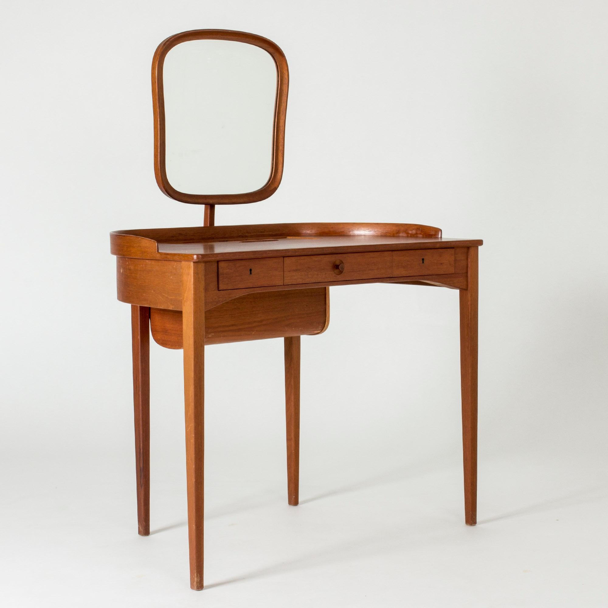 Beautiful “Birgitta” dressing table by Carl Malmsten, made from teak. Neat, curved design. Submerged drawer in the tabletop, covered by a jalousie door.