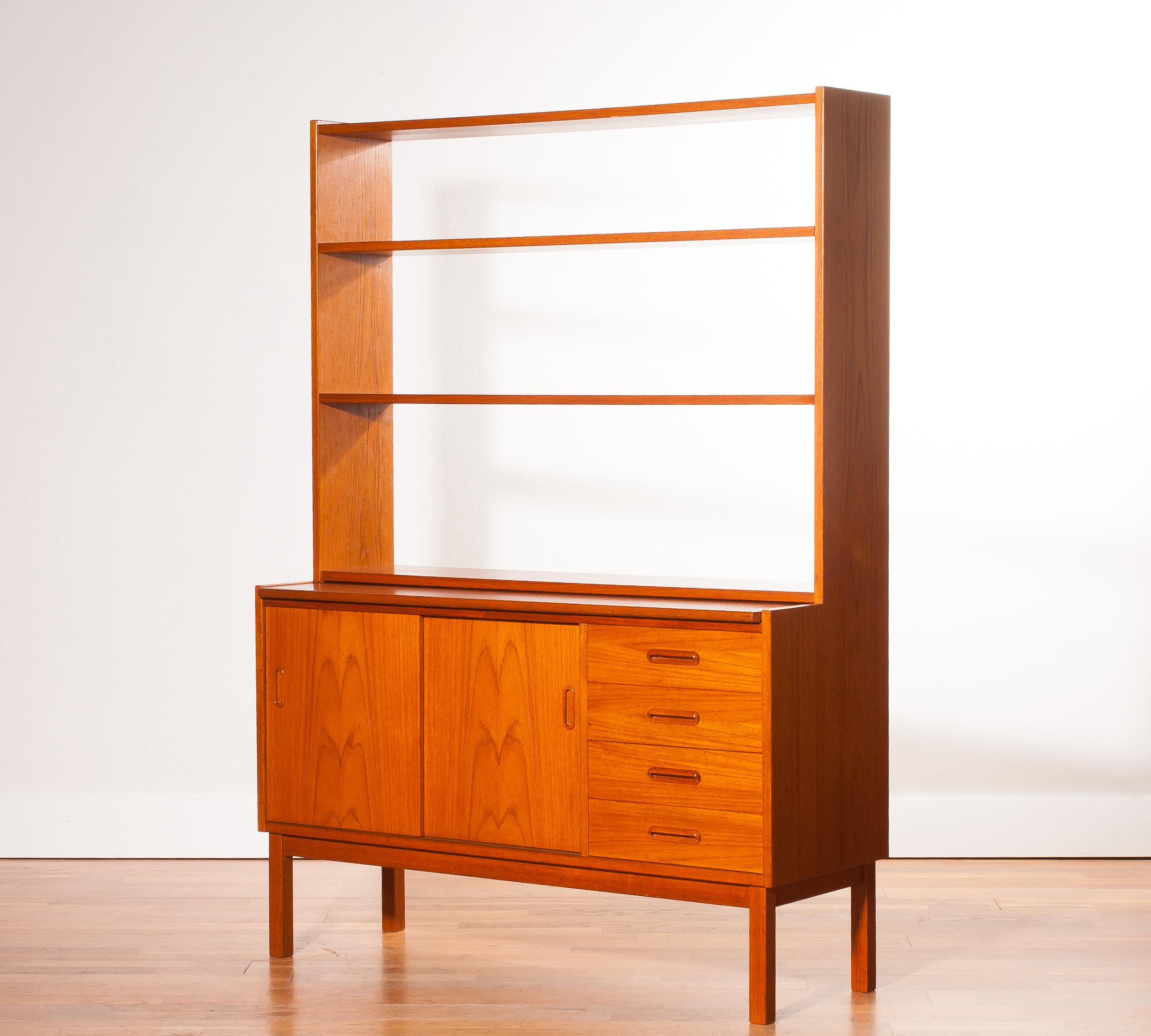 Very beautiful bookcase with slidable writing space produced in Sweden.
This cabinet is made of teak.
The cabinet has two sliding doors and four drawers.
With the writing sheet extended is the cabinet 62 cm deep and is the writing tablet 39 cm