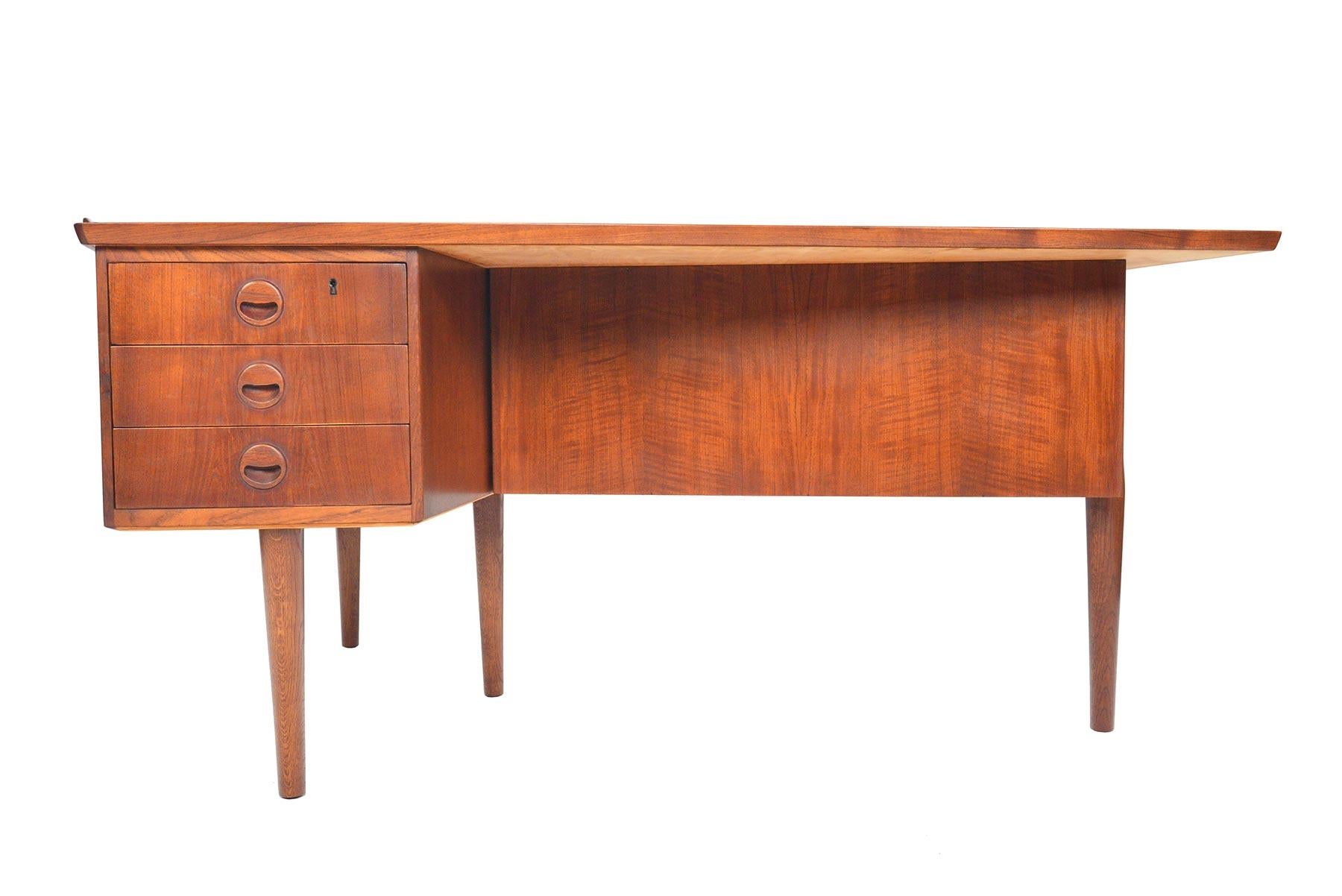 This rare and wonderful Danish modern boomerang desk in teak was designed by Arne Vodder in the 1960s. A marvel from every angle, this stunning piece features a left oriented bank of three drawers for storage. The back of this desk features a black