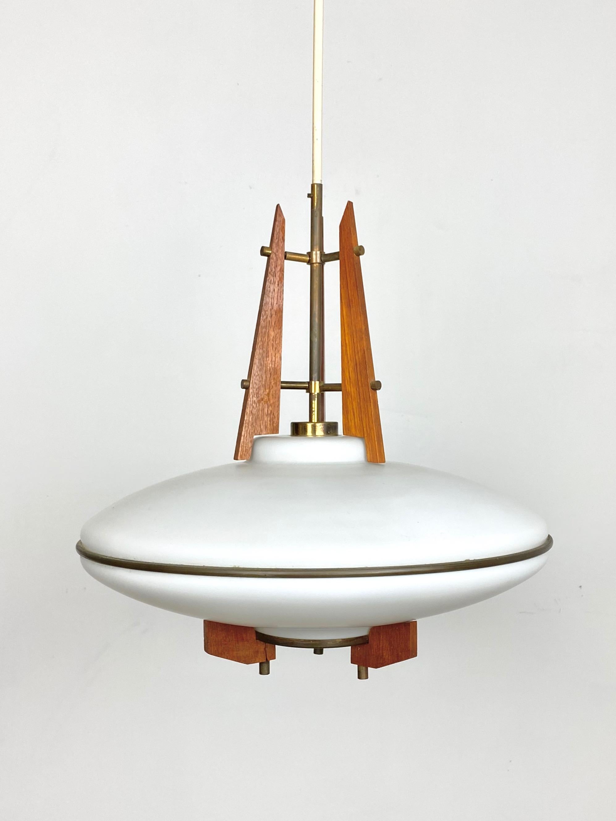 This beautiful and rare pendant was produced in Italy in the early 1960s. Its design and its high quality resemble the contemporary Stilnovo production. The lamp is made from a sandblasted opaline glass shade supported by 3 shaped teak holders with
