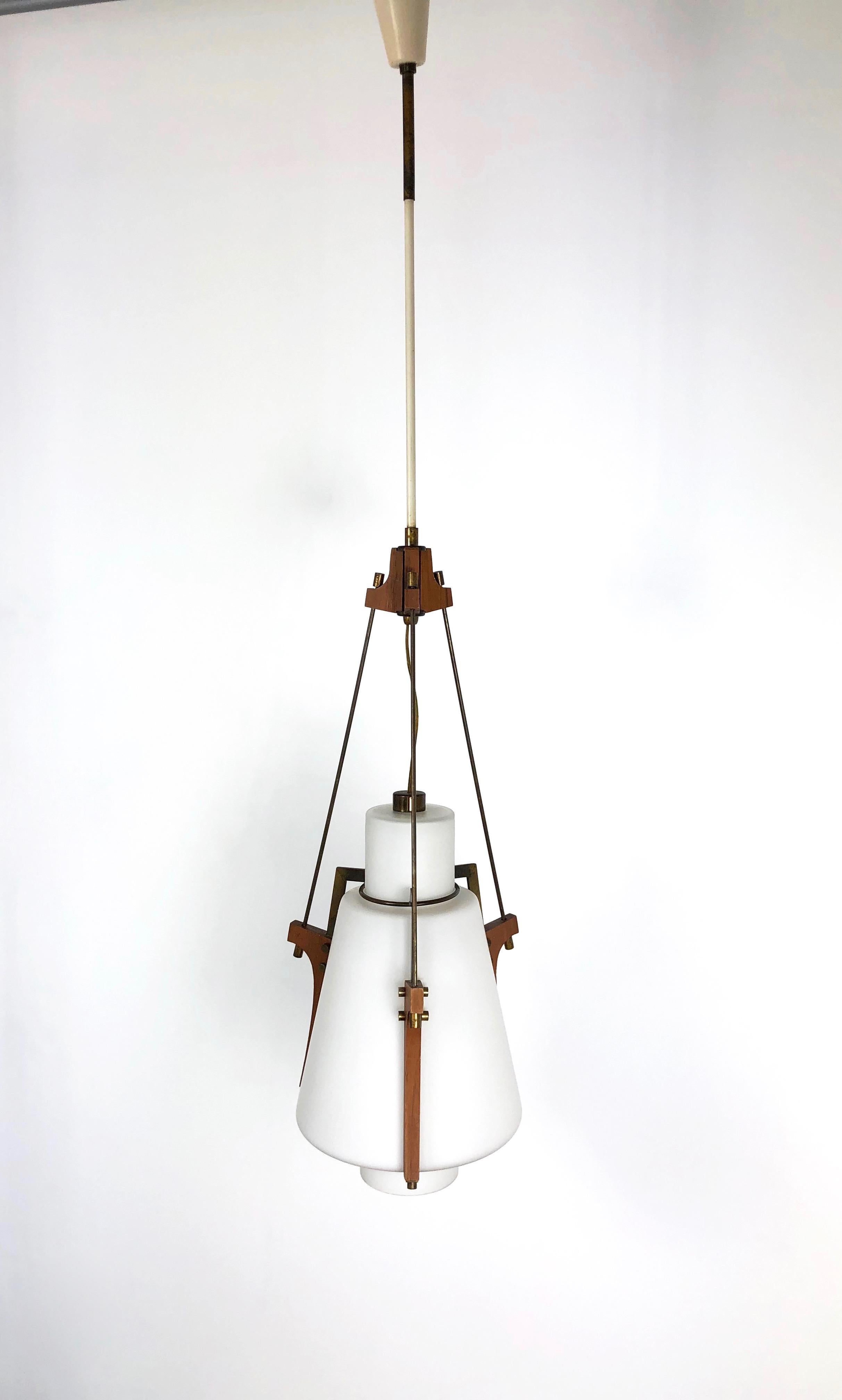 This beautiful and rare pendant was produced in Italy in the early 1960s. Its design and its high quality resemble the contemporary Stilnovo production. The lamp is made from a sandblasted opaline glass shade supported by 3-shaped teak holders with