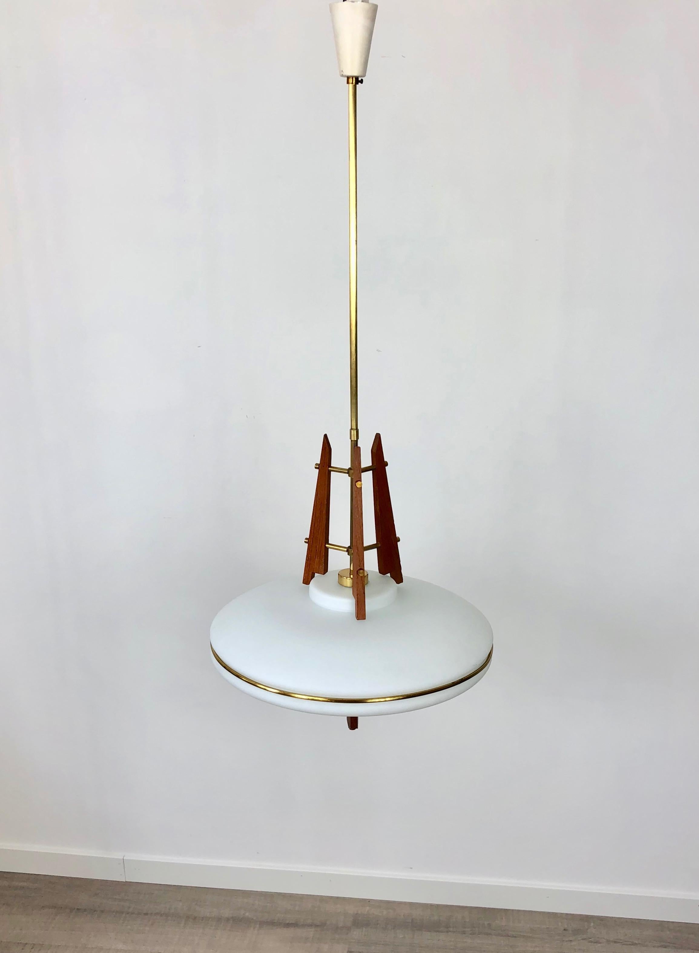 This beautiful and rare pendant was produced in Italy in the early 1960s. Its design and its high quality resemble the contemporary Stilnovo production. The lamp is made from a sandblasted opaline glass shade supported by 3 shaped teak holders with